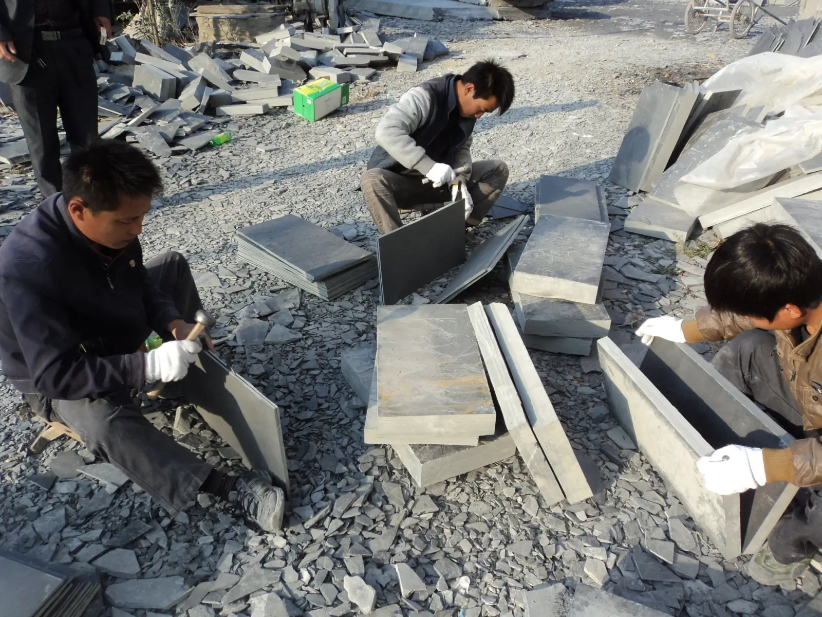 Worker hand-splitting natural roofing slate in Jiujiang, China