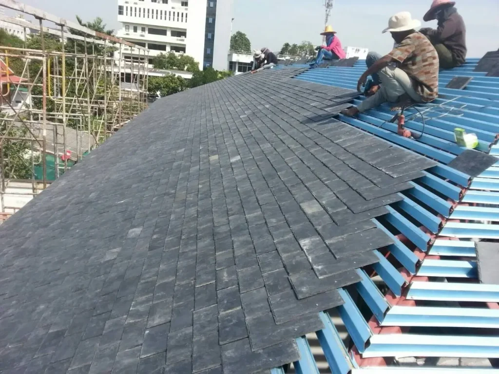 Professional installation of natural blue-grey roofing slate on a pitched roof using correct fixing methods.