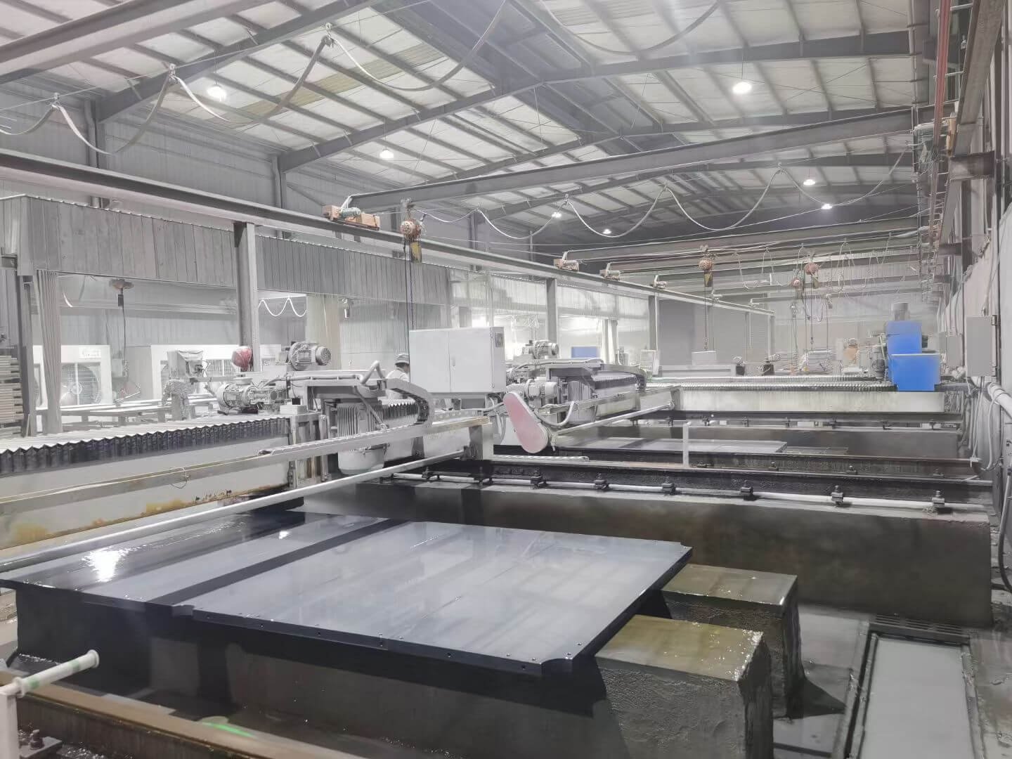 Billiard slate manufacturing floor: grinding, drilling and processing Billiard slate production floor with grinding equipment, overhead crane, and processed slate panels on the workbed