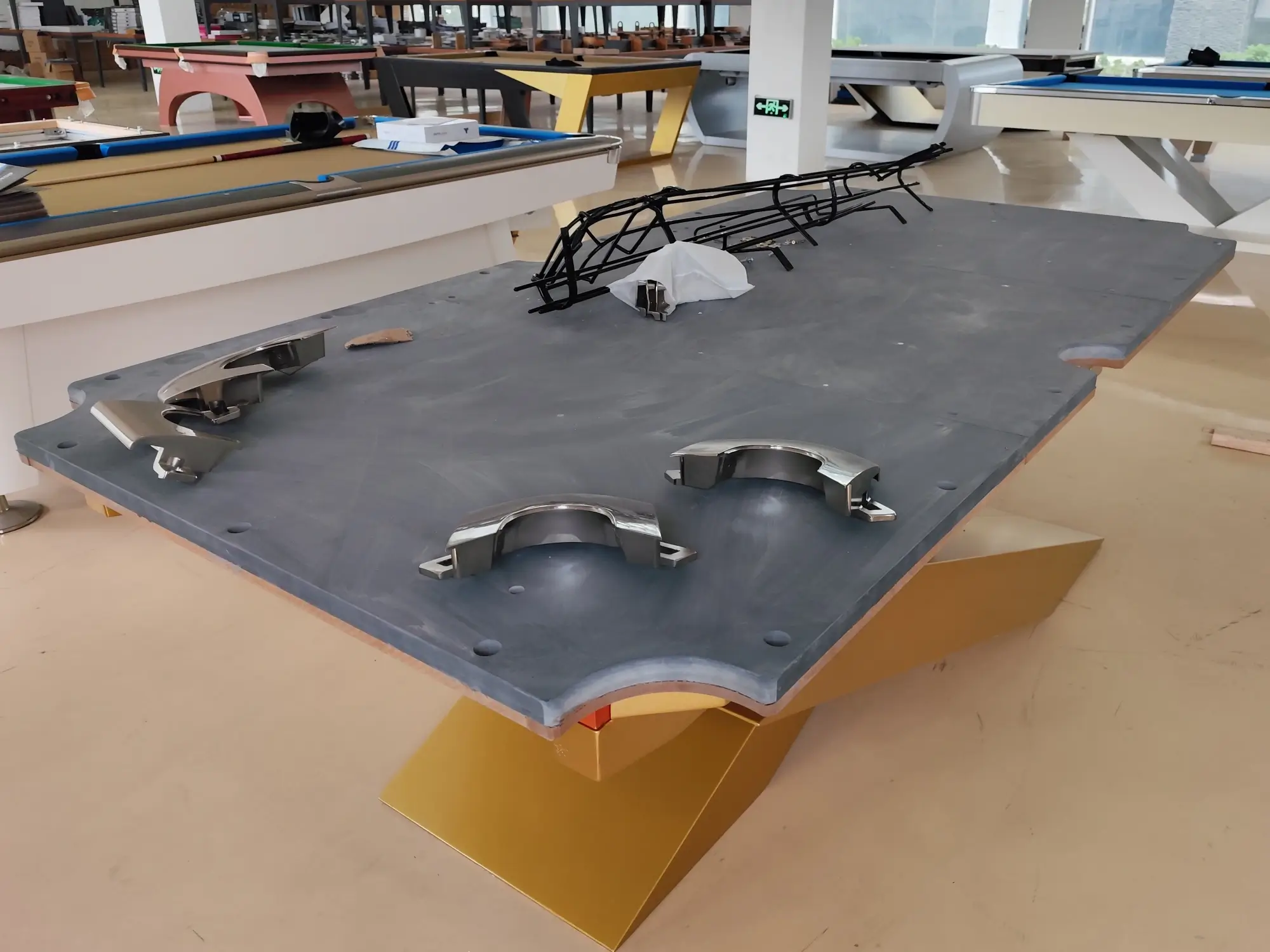 Billiard Slate as a Table Component Bare slate panel fitted edge to edge in a wooden billiard table frame inside a table manufacturing workshop