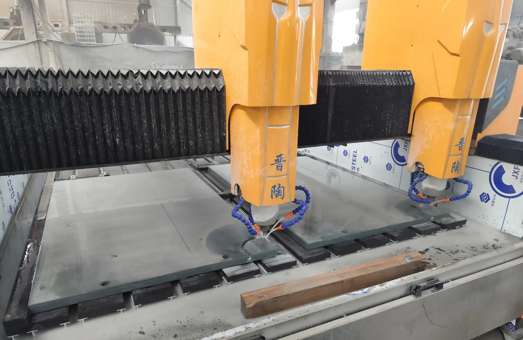 CNC Machining Billiard Slate Close-up of a CNC milling cutter grinding the edge of a dark grey slate panel with stone slurry spraying at the contact point