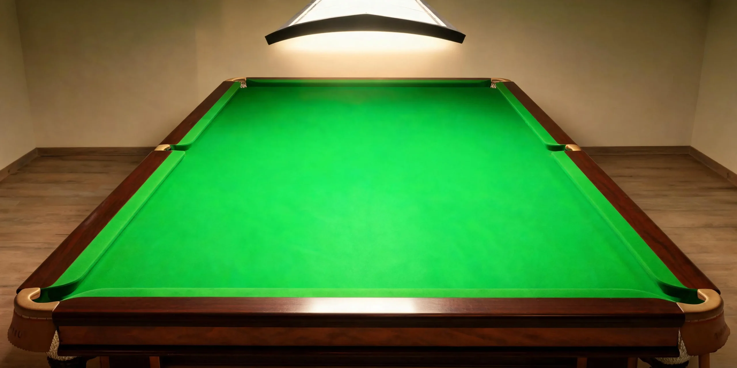 The final milestone — a finished snooker table ready for play Completed snooker table with green cloth under a single overhead light in a quiet club room