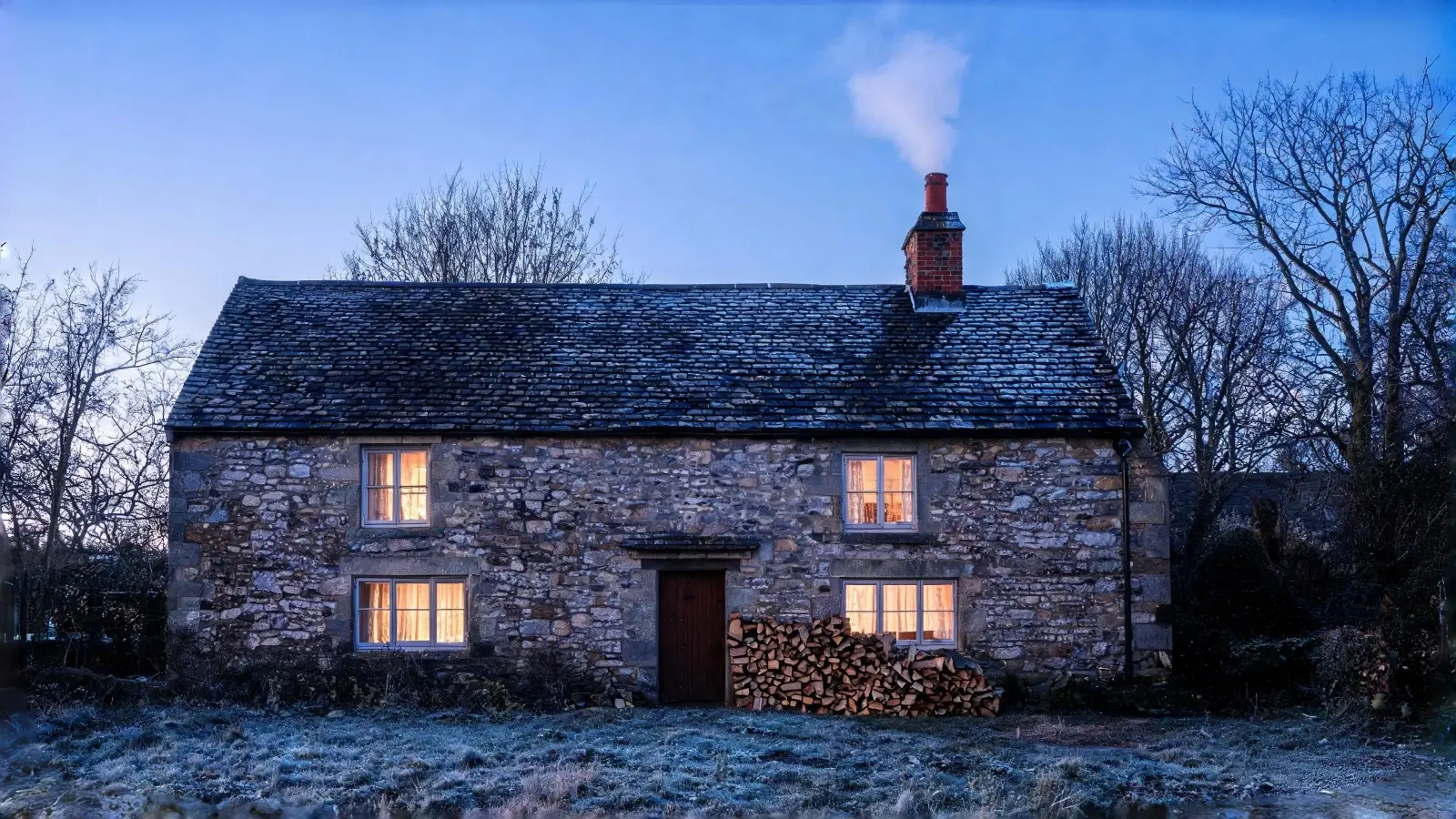 Cottage chimney below a natural slate roof in evening light