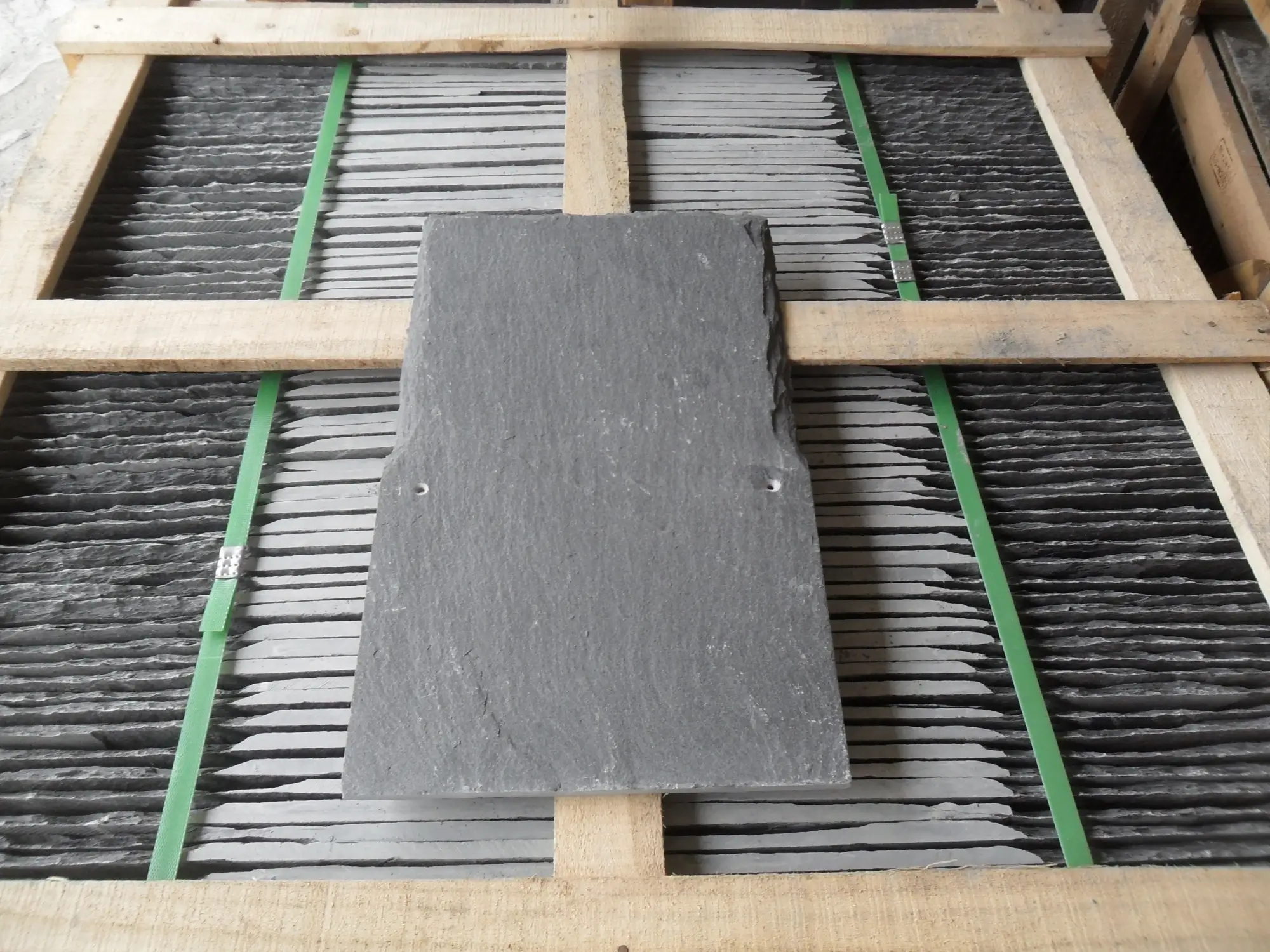 Neat stack of finished grey roofing slate tiles showing natural cleft surface