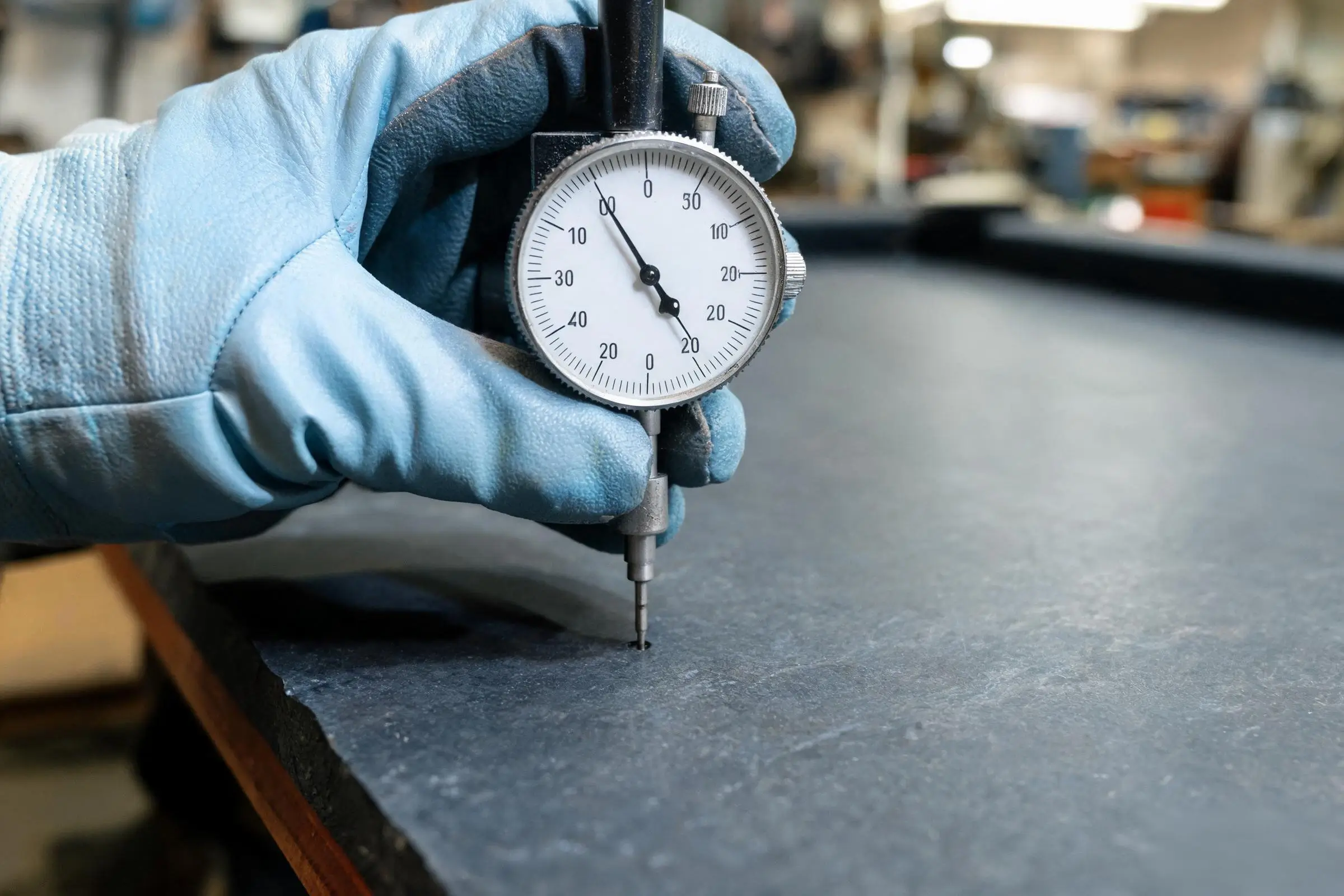 Jiujiang Slate Flatness & Dimensional Stability 6 A precision dial indicator gauge measuring the surface flatness of a dark slate panel with the probe in contact with the stone surface