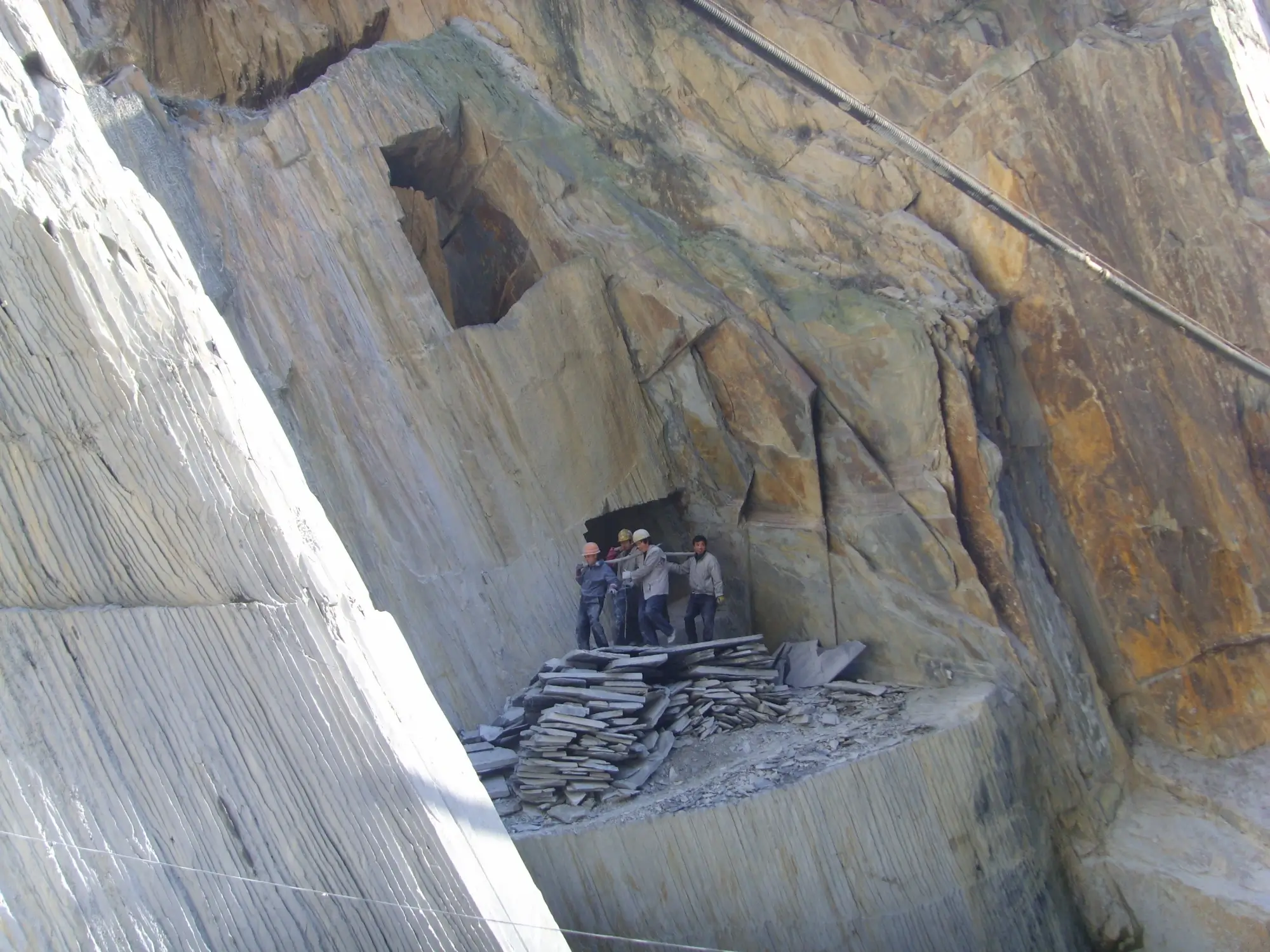 The Jiujiang Slate Industry 2 Close-up of a natural slate quarry rock face showing horizontal layered grey strata