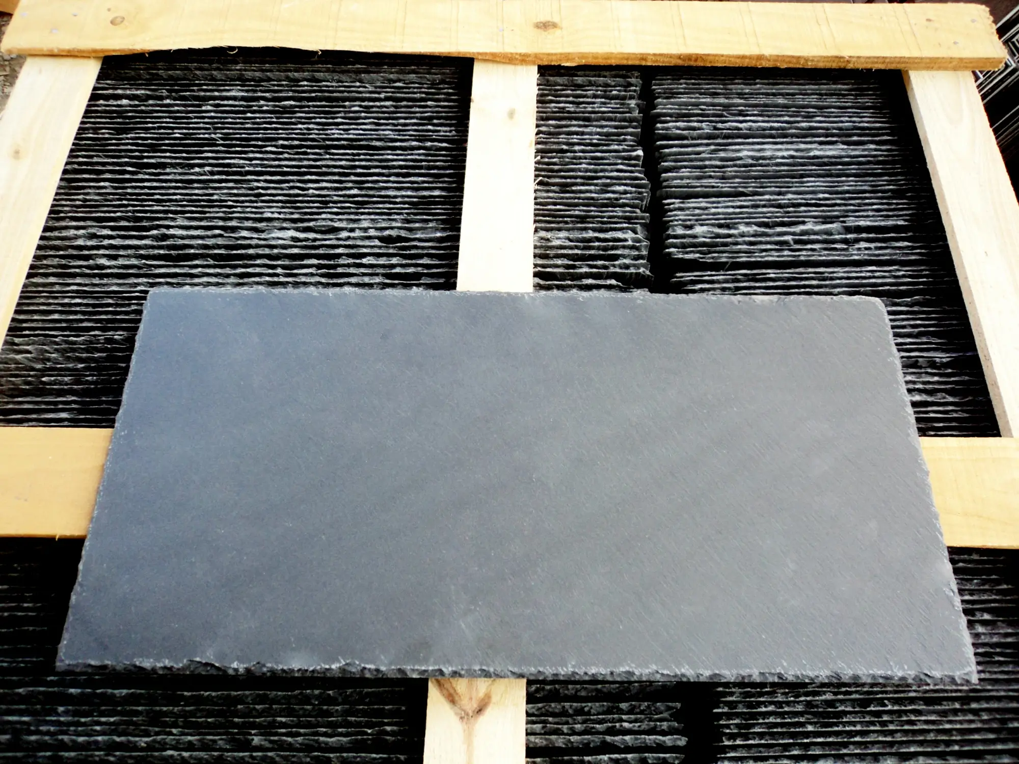 Two laboratory test reports for roofing slate from different origins placed side by side on a desk