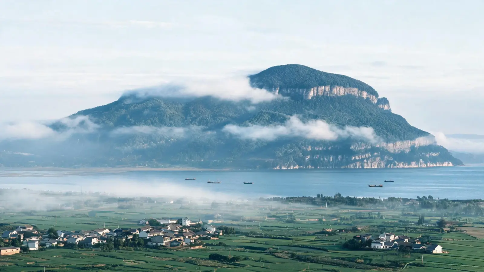 Mount Lushan rising above the plains beside Poyang Lake, with farmland and villages in the foreground, Jiujiang slate region, Jiangxi China