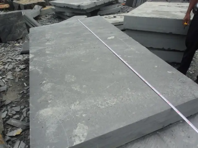 Measuring a slate block against the order dimensions Worker measuring a large slate block with a tape measure to judge billiard bed feasibility
