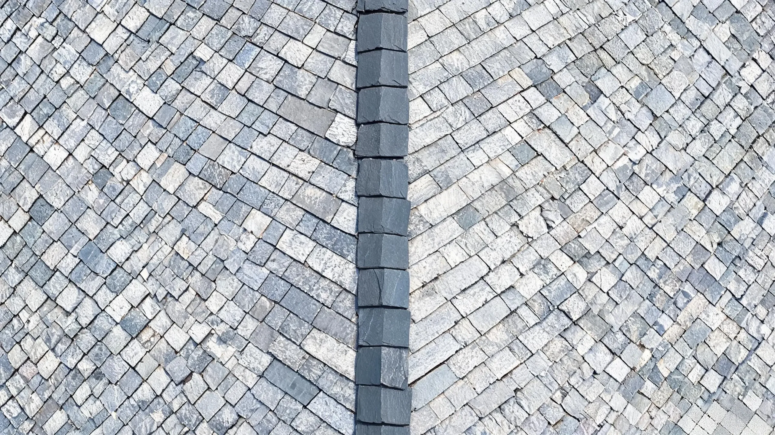 Patched slate roof valley showing individual tile replacements Aerial view of patched slate roof valley with replacement tiles