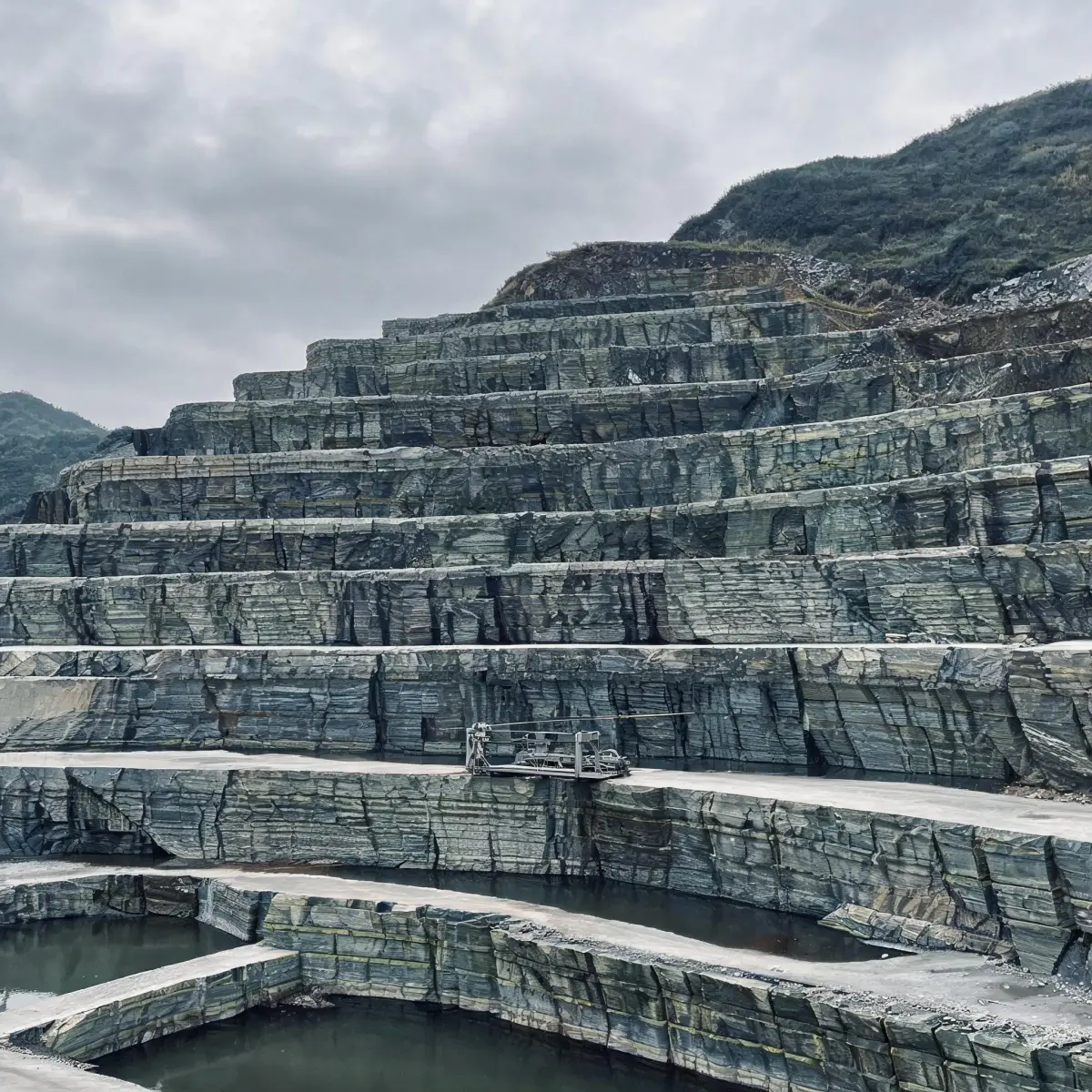 Restored slate quarry with terraced cliff and climbing vines
