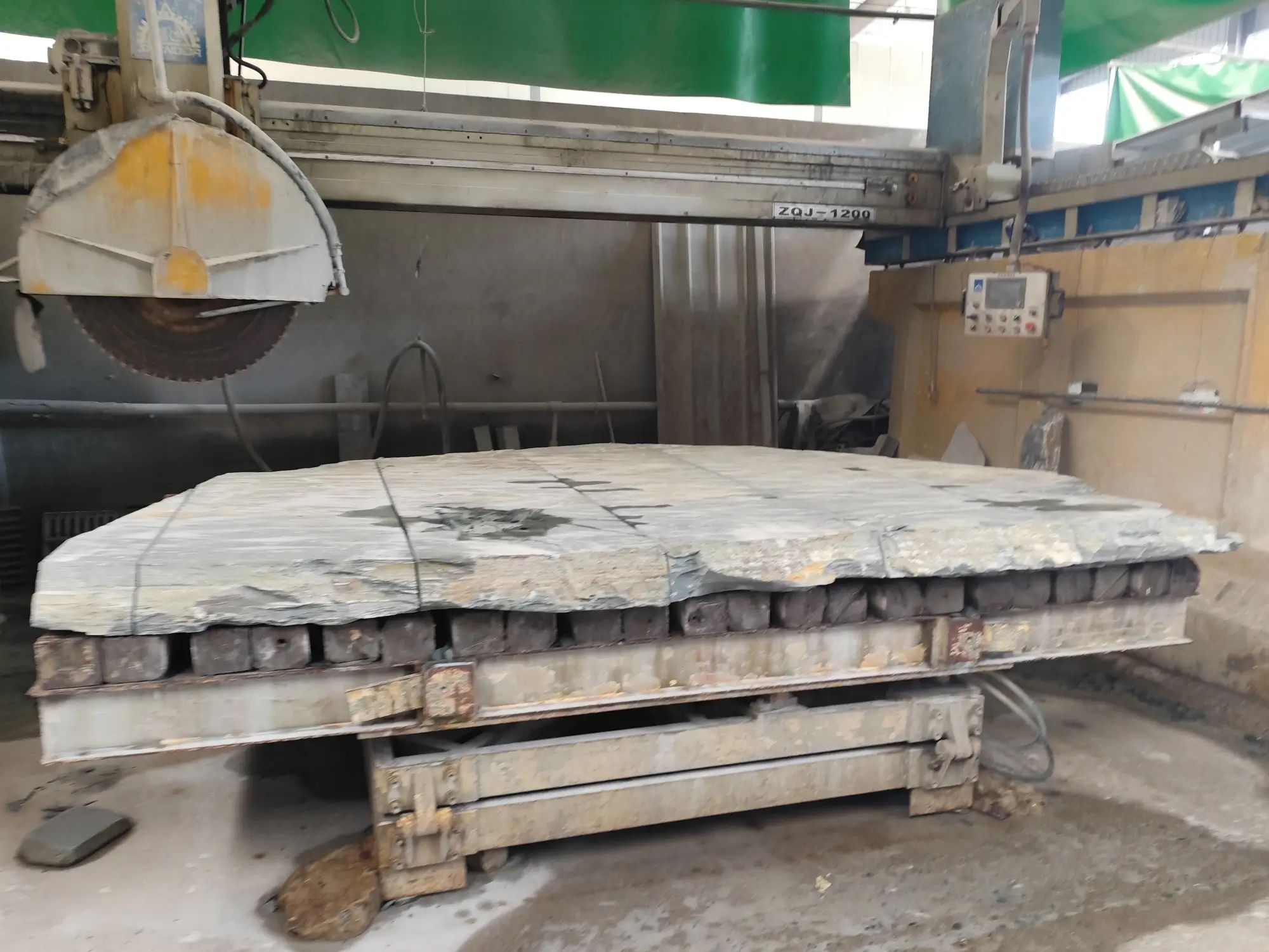 Raw slate slab before cutting A very large raw slate slab lying flat in a workshop, its rough cleaved edge catching the light