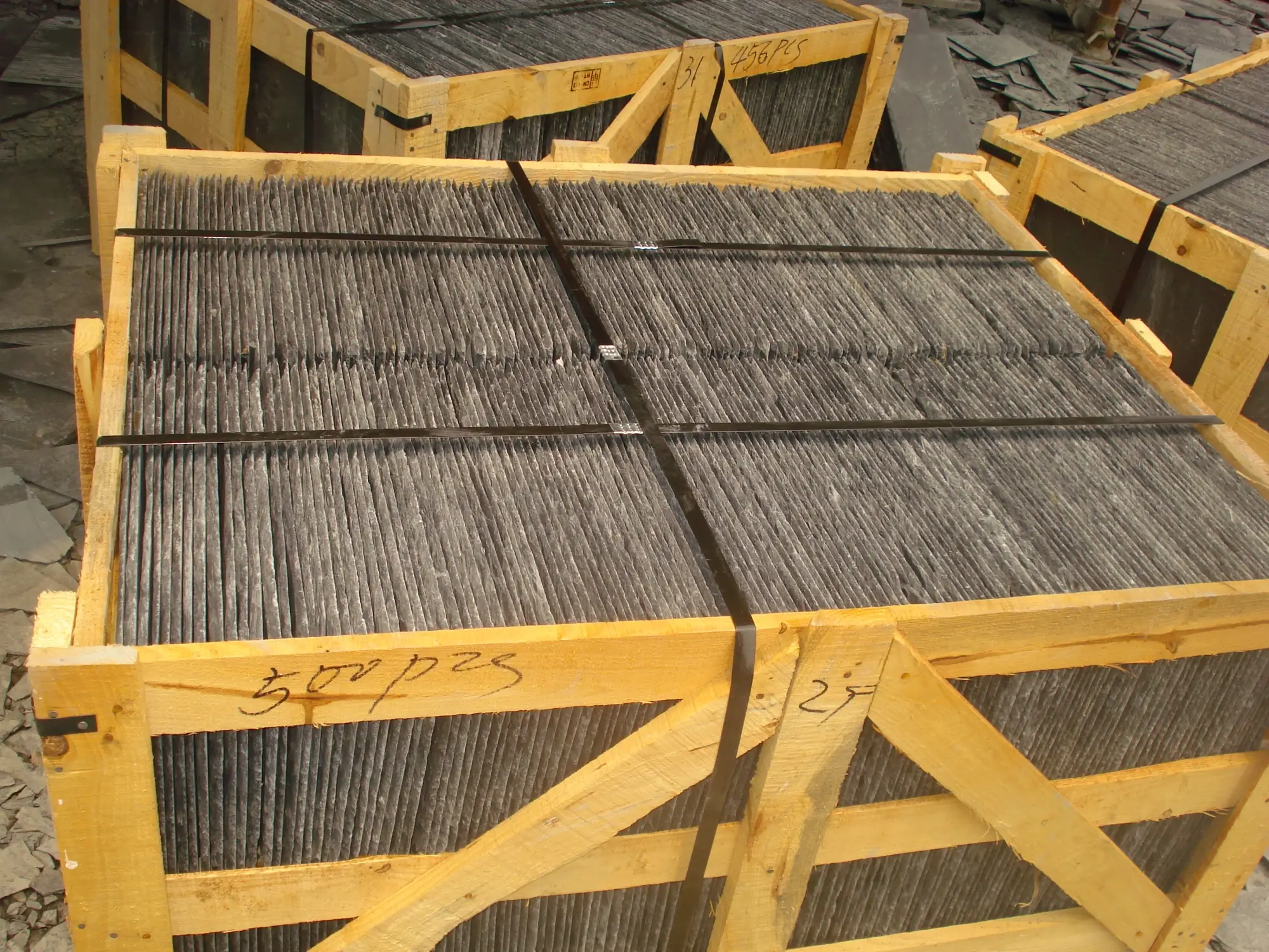 Roofing slate packed into a wooden export crate Wooden export crate half filled with stacked grey roofing slate tiles with protective separators between layers