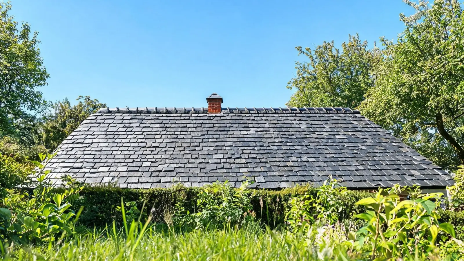Roofing Slate FAQ 6 A well-maintained slate roof viewed from ground level on a clear day