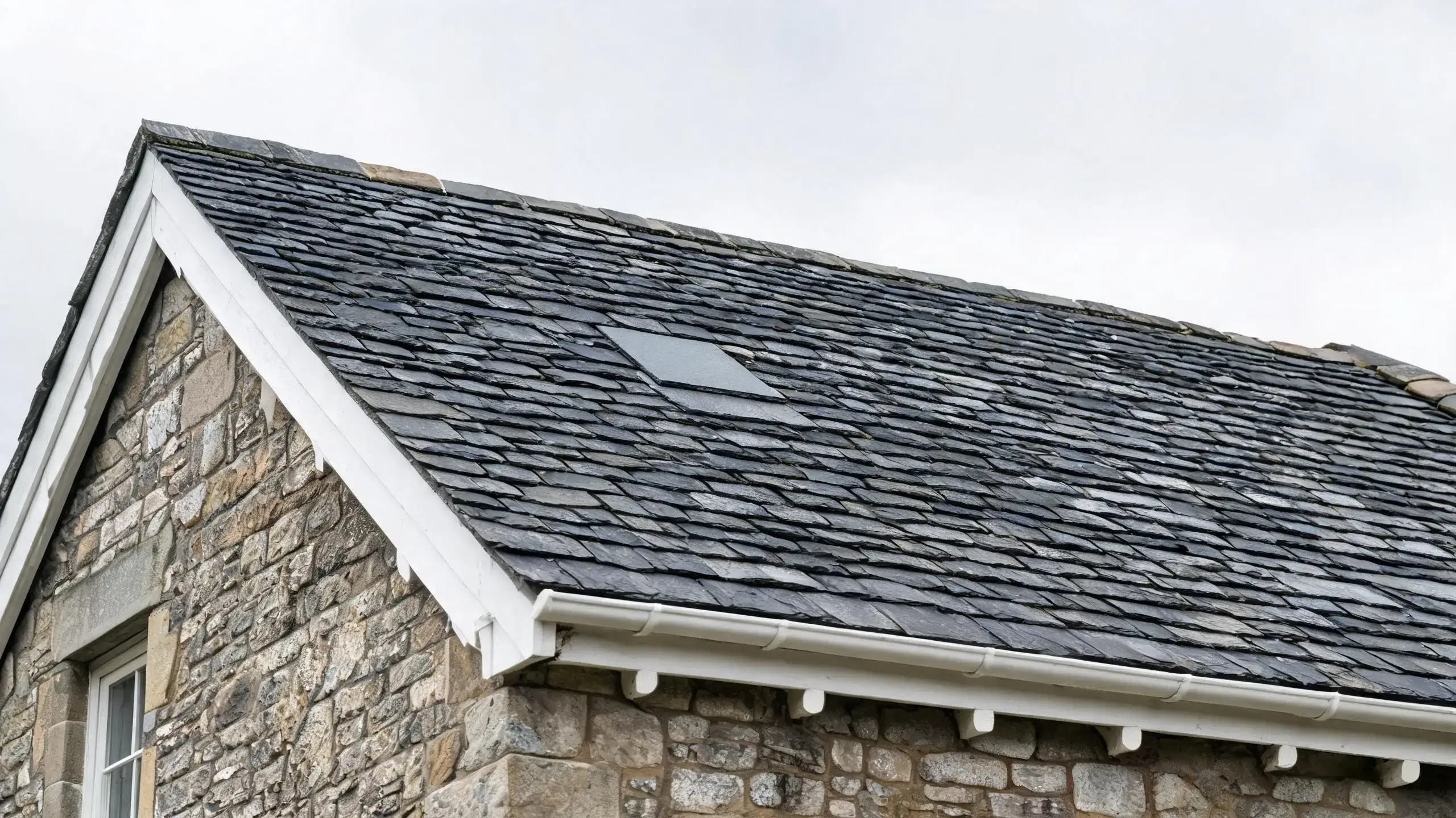 Seamless slate roof patch with a matched replacement tile blending into old weathered slates