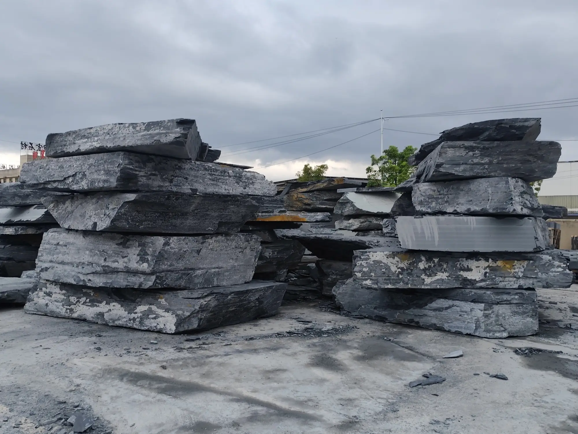How to Source Jiujiang Slate Directly 2 Slate blocks stacked in a factory yard with workshop buildings behind