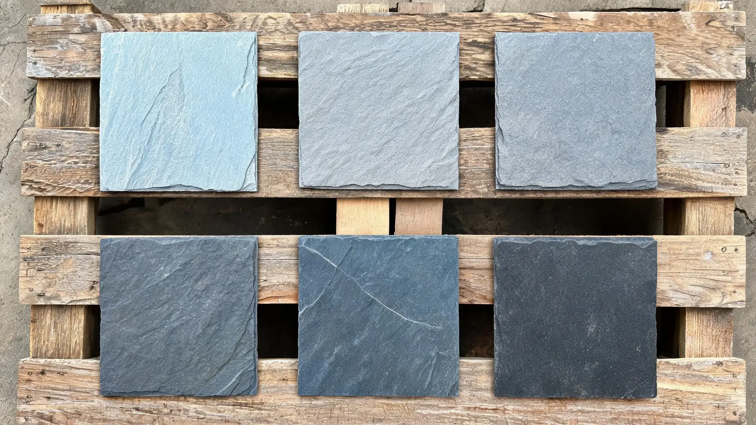 Six roofing slate samples in graduated shades of grey showing natural colour variation between batches