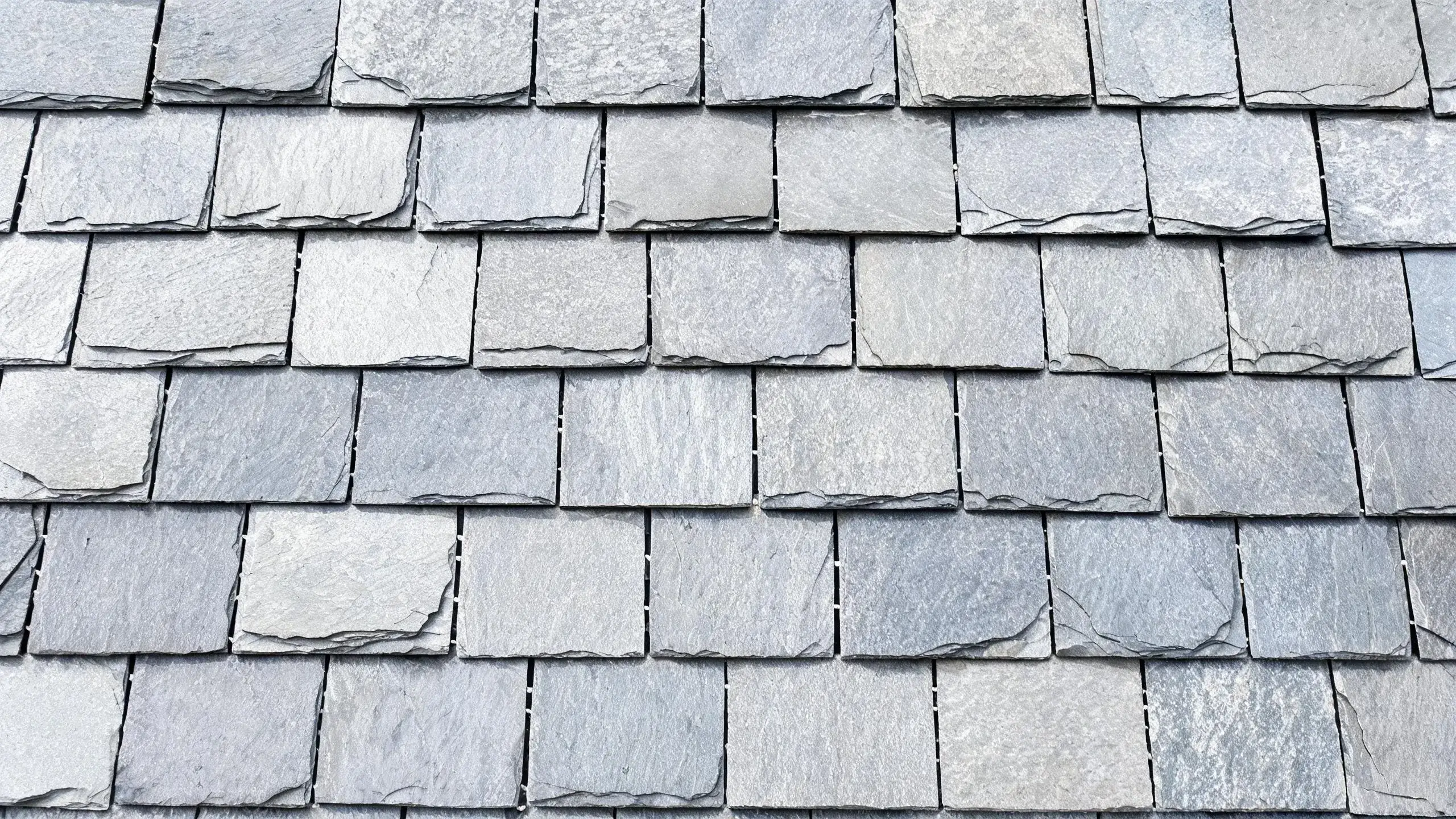 Close-up of a slate roof showing the staggered broken bond joint pattern between courses