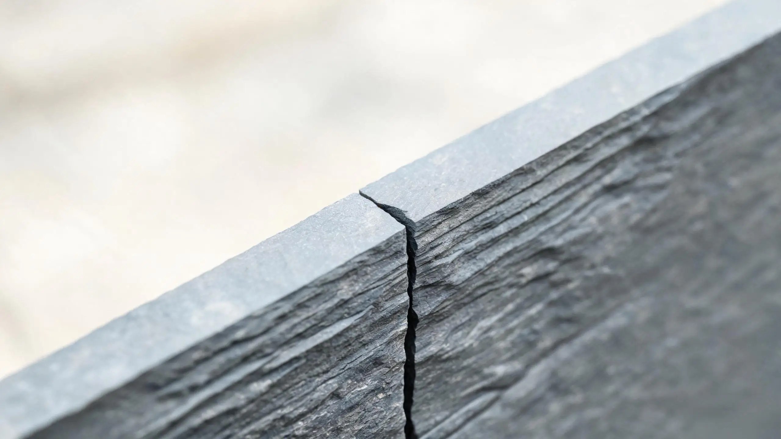 Slate sample edge and cleavage close-up Close-up of the sawn edge and natural cleft surface of a grey slate sample showing layered texture