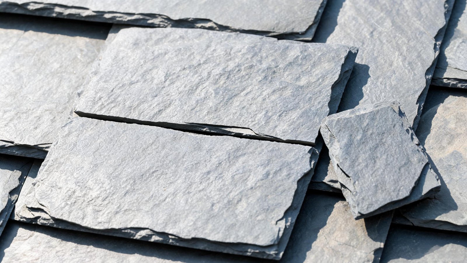 Slate tile cracked by foot traffic — a clean break across the centre A roofing slate tile with a straight crack across its middle from foot traffic