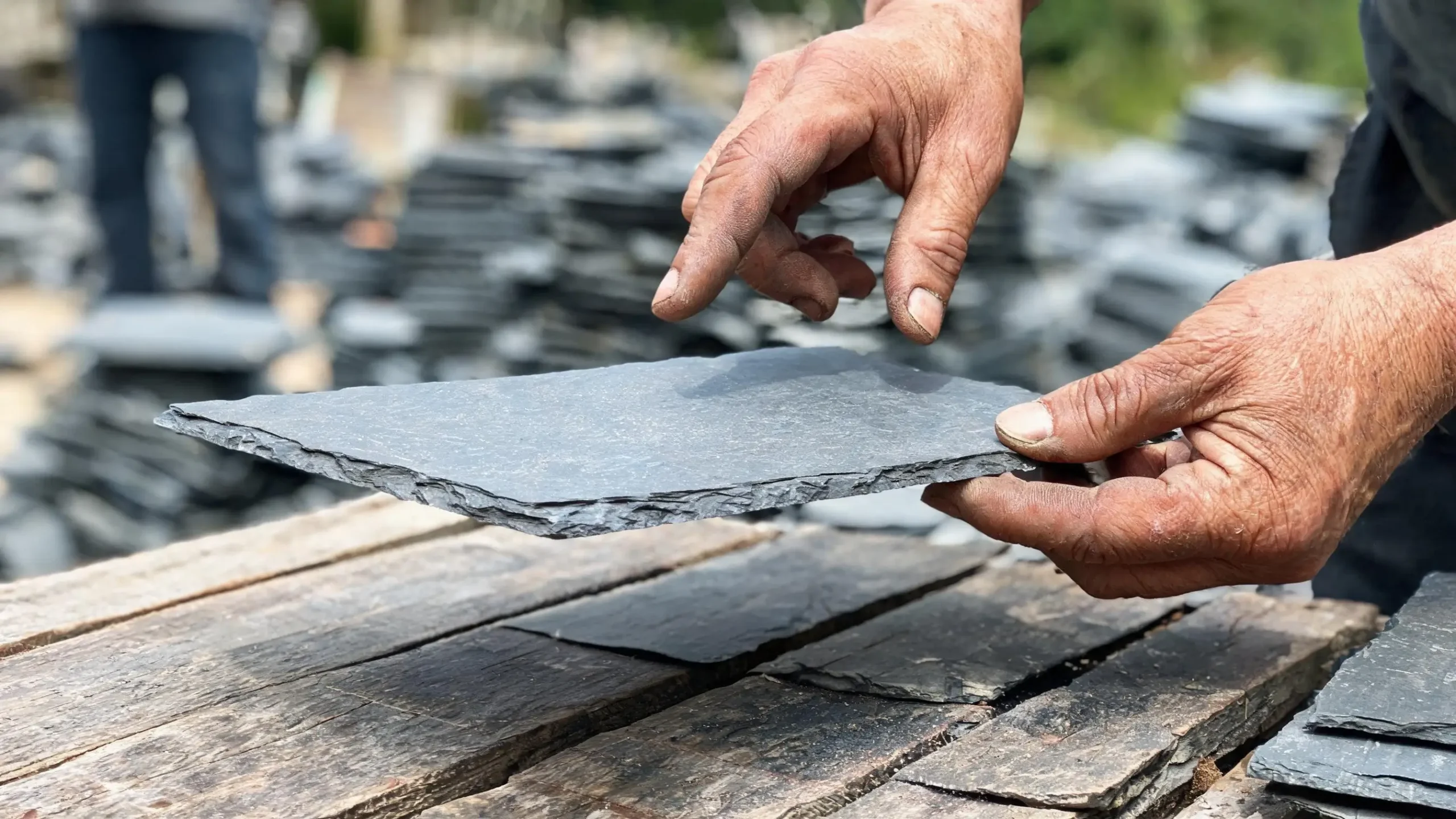 Reusing Existing Roofing Slate 3 Worker holding a salvaged slate tile on his fingertips and tapping the corner to listen for cracks