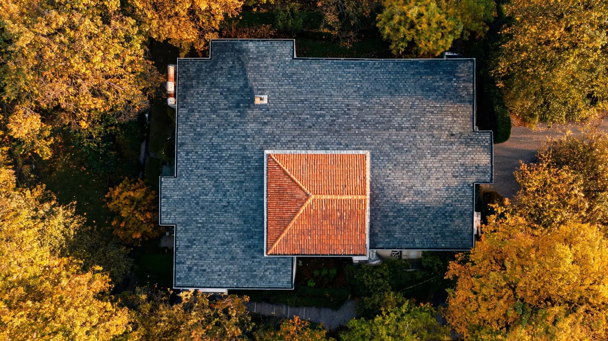 Aerial view of a country house with natural slate main roof and clay tile extension