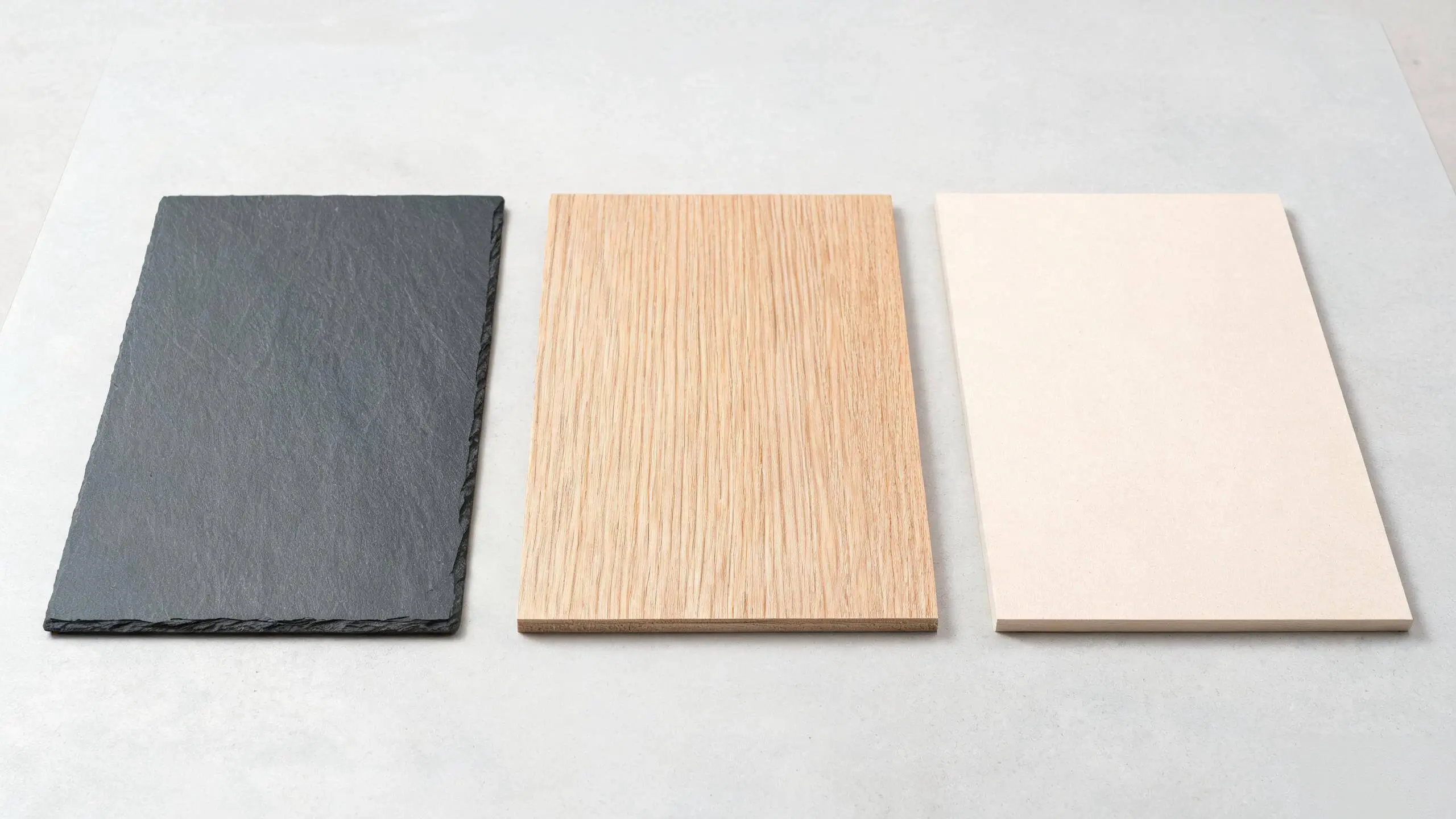 Three pool table bed materials side by side: dark slate slab, solid timber board and pale MDF board