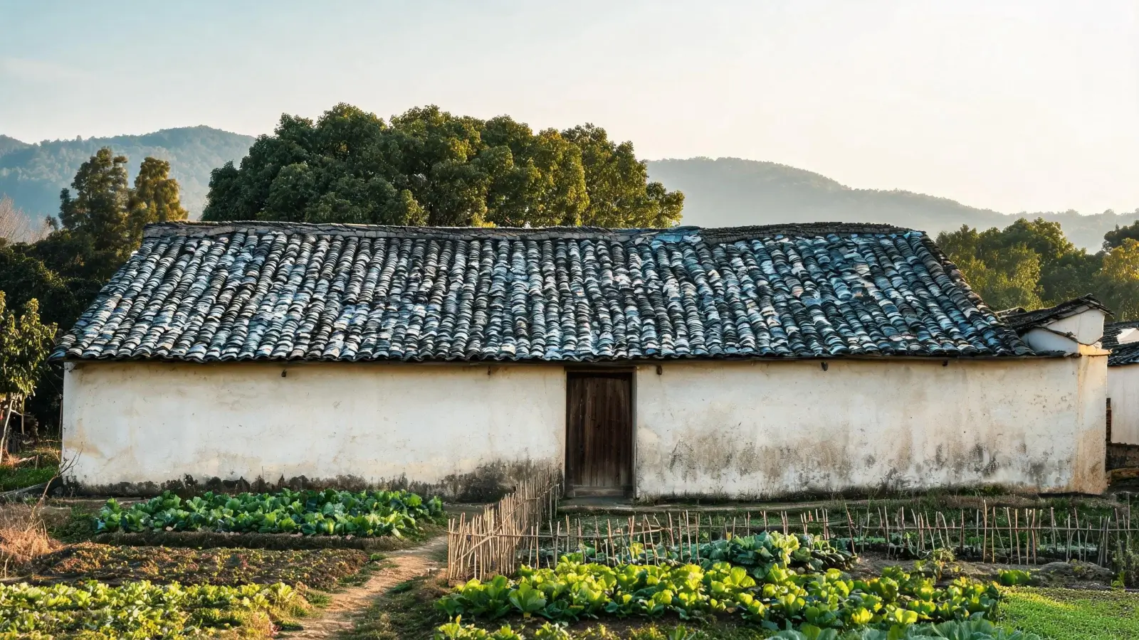 Lushan, Xingzi and the Slate Belt of Jiangxi 3 Traditional village house roofed with grey-blue natural slate tiles in the Lushan foothills near Xingzi, Jiangxi China — cleft tile surfaces, weathered edges, vegetable plot and hazy hills behind