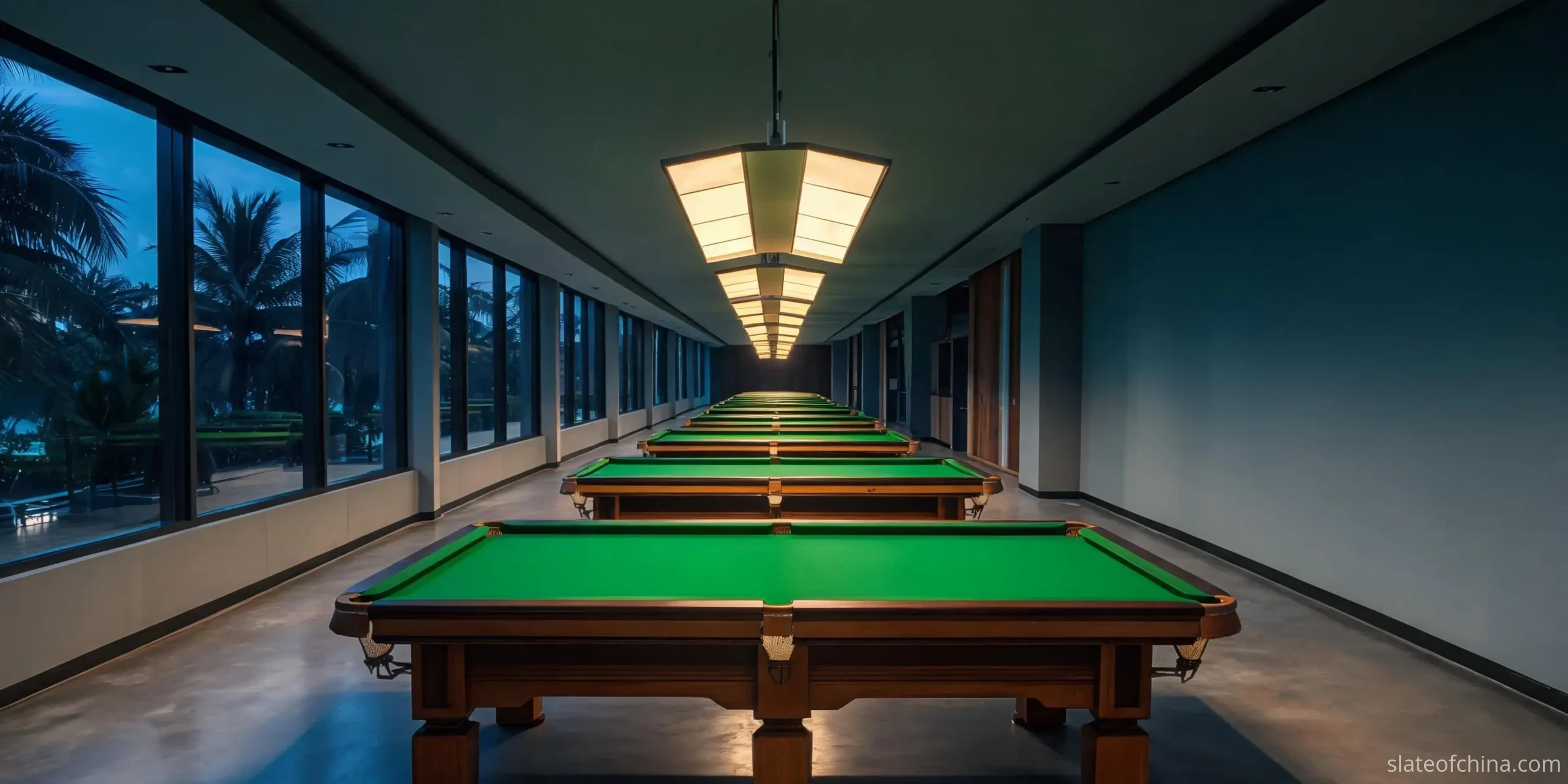 A row of pool tables under pendant lights in a Southeast Asian billiard hall at dusk