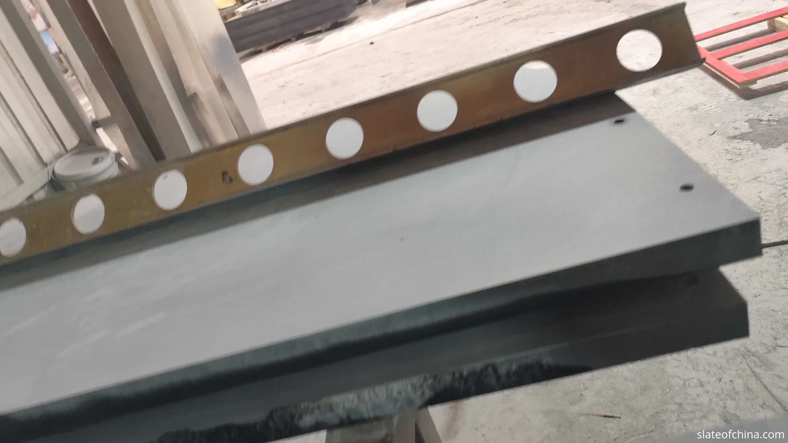 Billiard Slate FAQ 3 A finished billiard slate panel on an inspection bench, a low-angle beam of raking light travelling across the honed matte surface