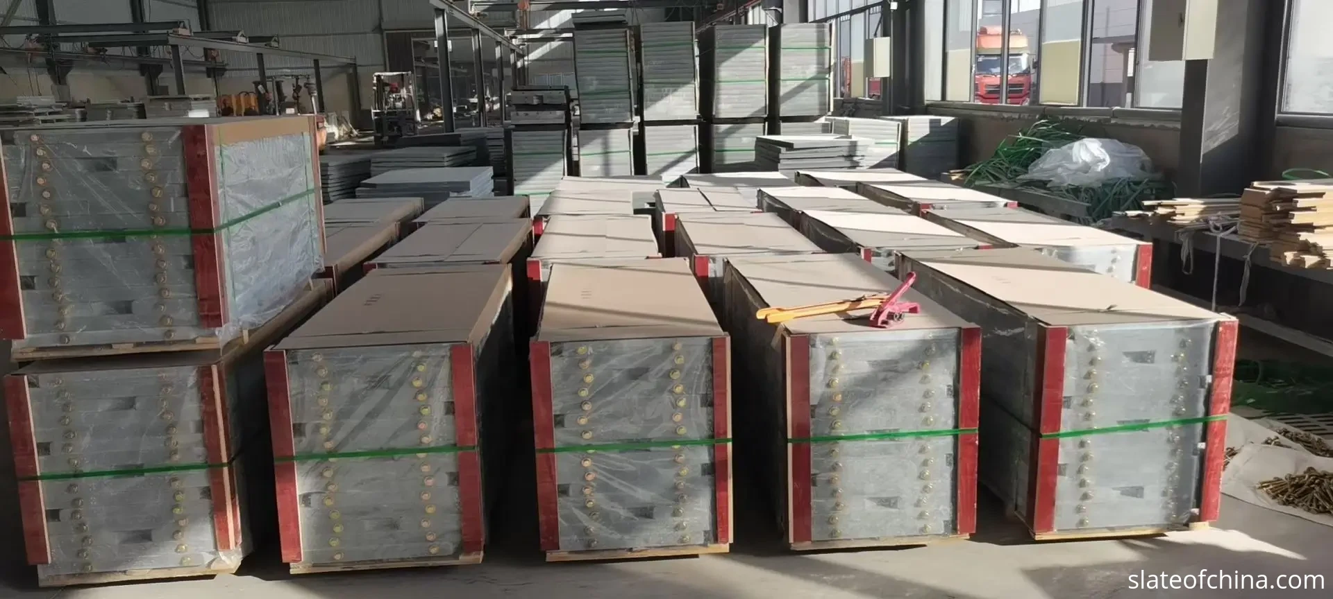 Billiard Slate FAQ 1 Finished billiard slate panels stacked on wooden pallets in rows inside a slate factory warehouse, the top panel of the nearest stack a long machined rectangle about twice as long as wide