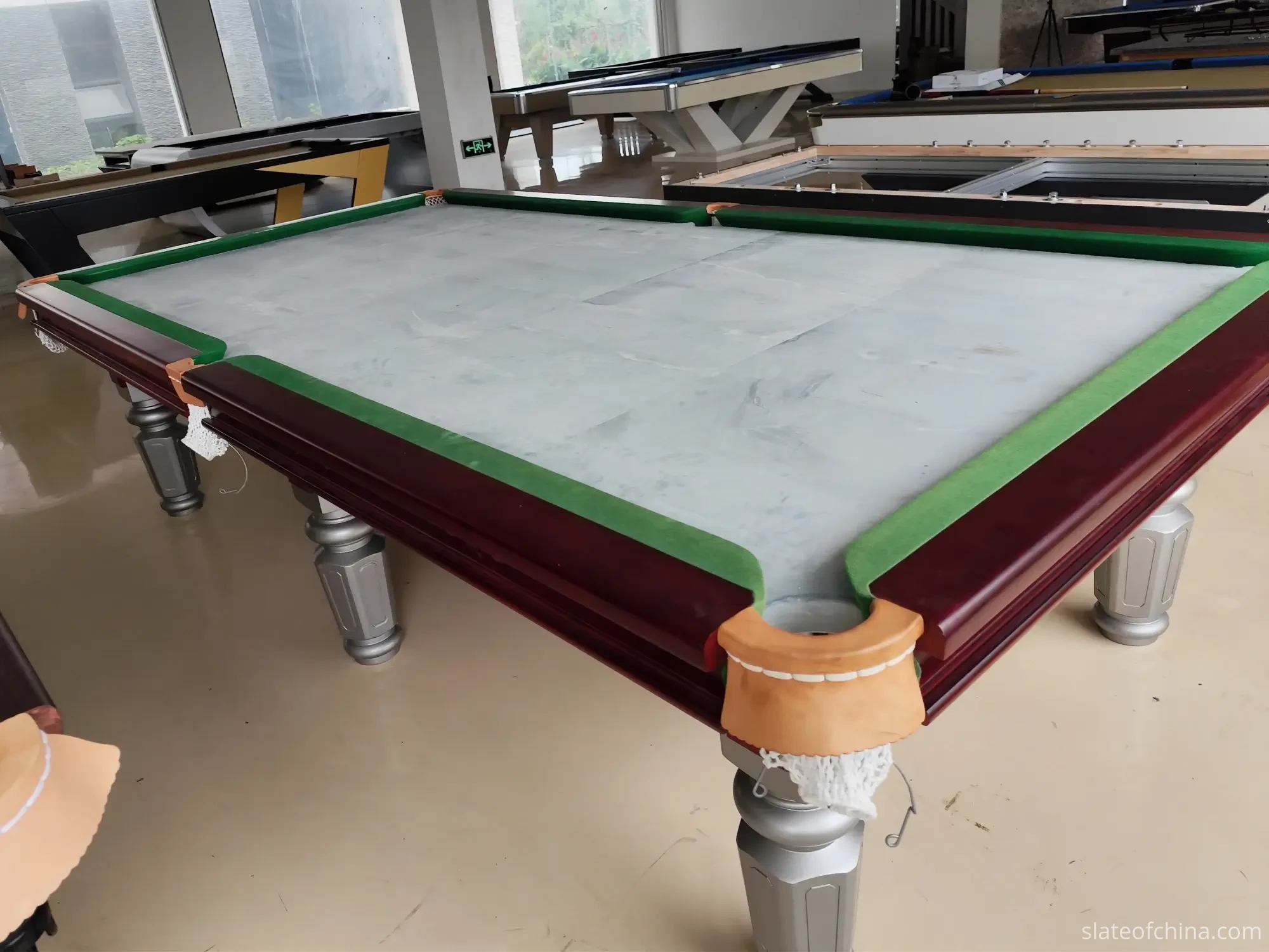 How Slate Flatness Affects Ball Roll 1 Three-piece billiard slate bed fitted into a mahogany pool table before the cloth, the seams between the three panels visible in a showroom light