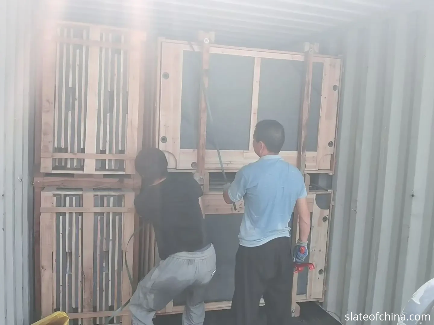 2026 Billiard Slate Industry Report 6 Workers securing wooden crates of packed billiard slate inside a shipping container during export loading