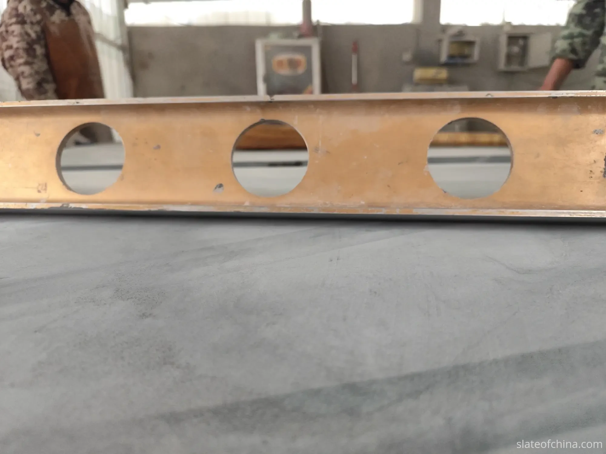 OEM Billiard Slate Manufacturing Process 4 Two workers using a long golden straightedge to check the flatness of a finished billiard slate panel laid flat in the workshop