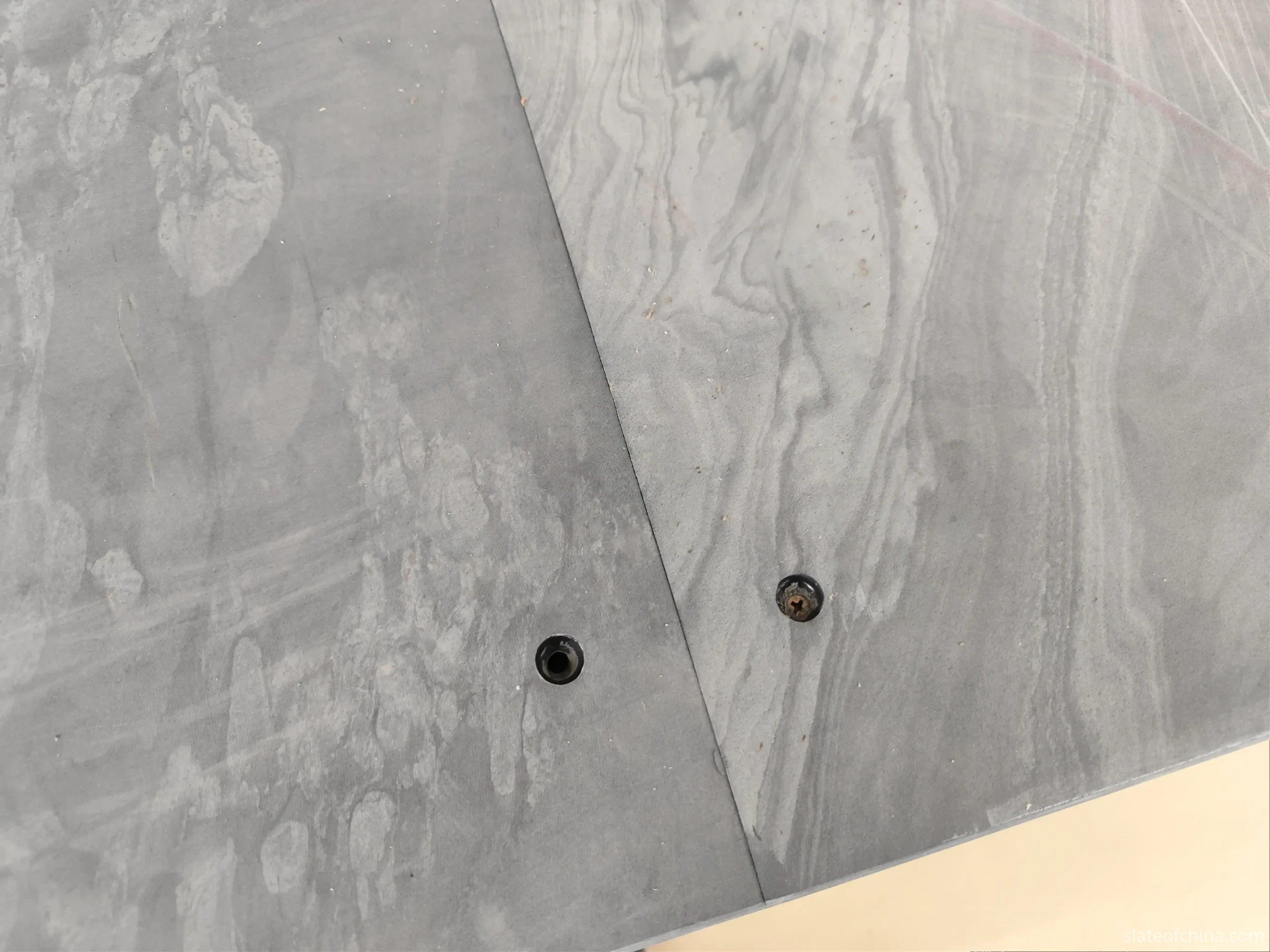 Machined joint seam between billiard slate panels Close-up overhead view of the tight seam between two billiard slate panels, showing the joint line and countersunk fastener holes