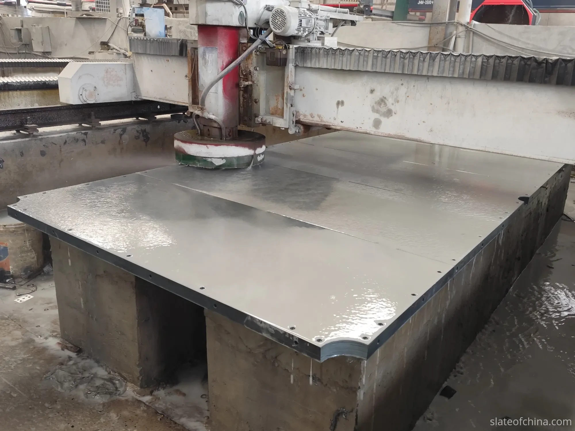 Slate Surface Grinding — Billiard Slate Factory Scene Bridge-type surface grinding machine working the playing face of a billiard slate panel under water spray