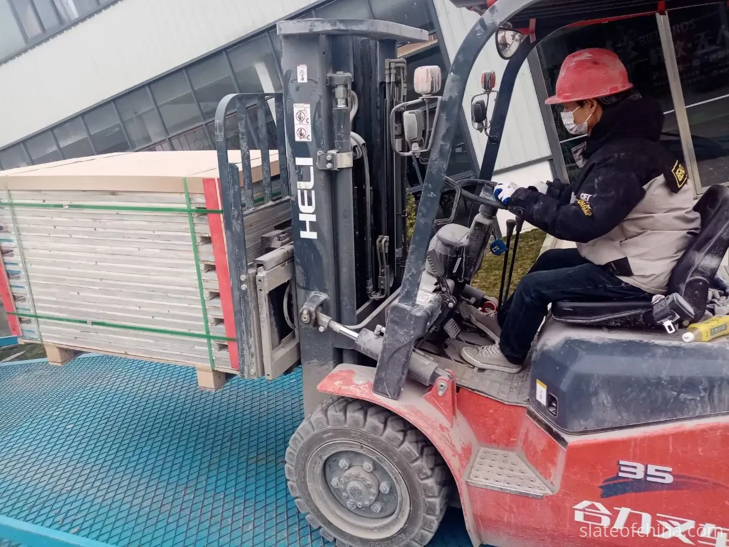 Forklift weighing a strapped pallet of billiard slate panels before container loading — gross weight drives freight planning