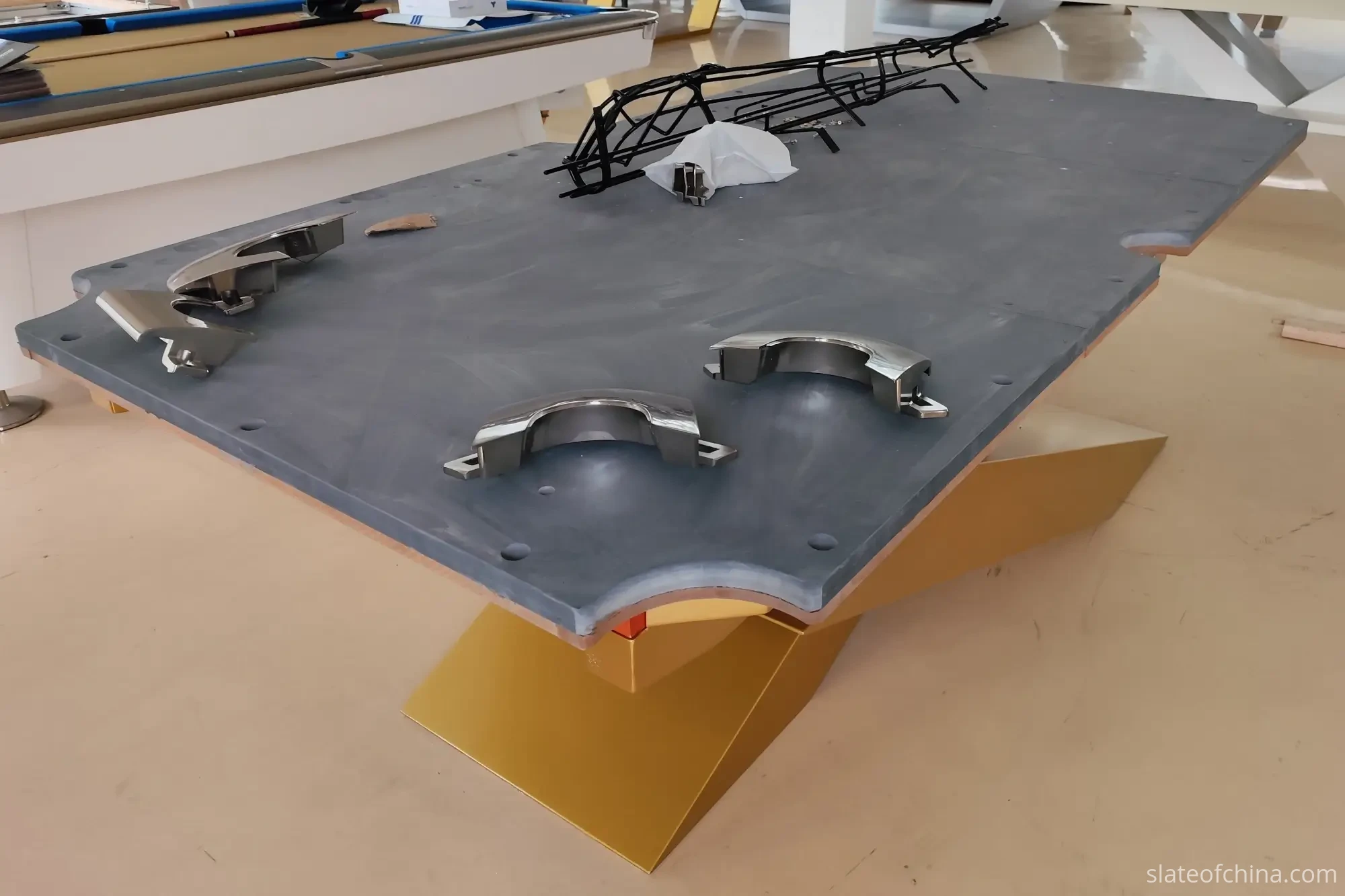 Three-piece billiard slate assembly on table frame Three-piece billiard slate set placed on a table frame during assembly, with visible seams between the panels