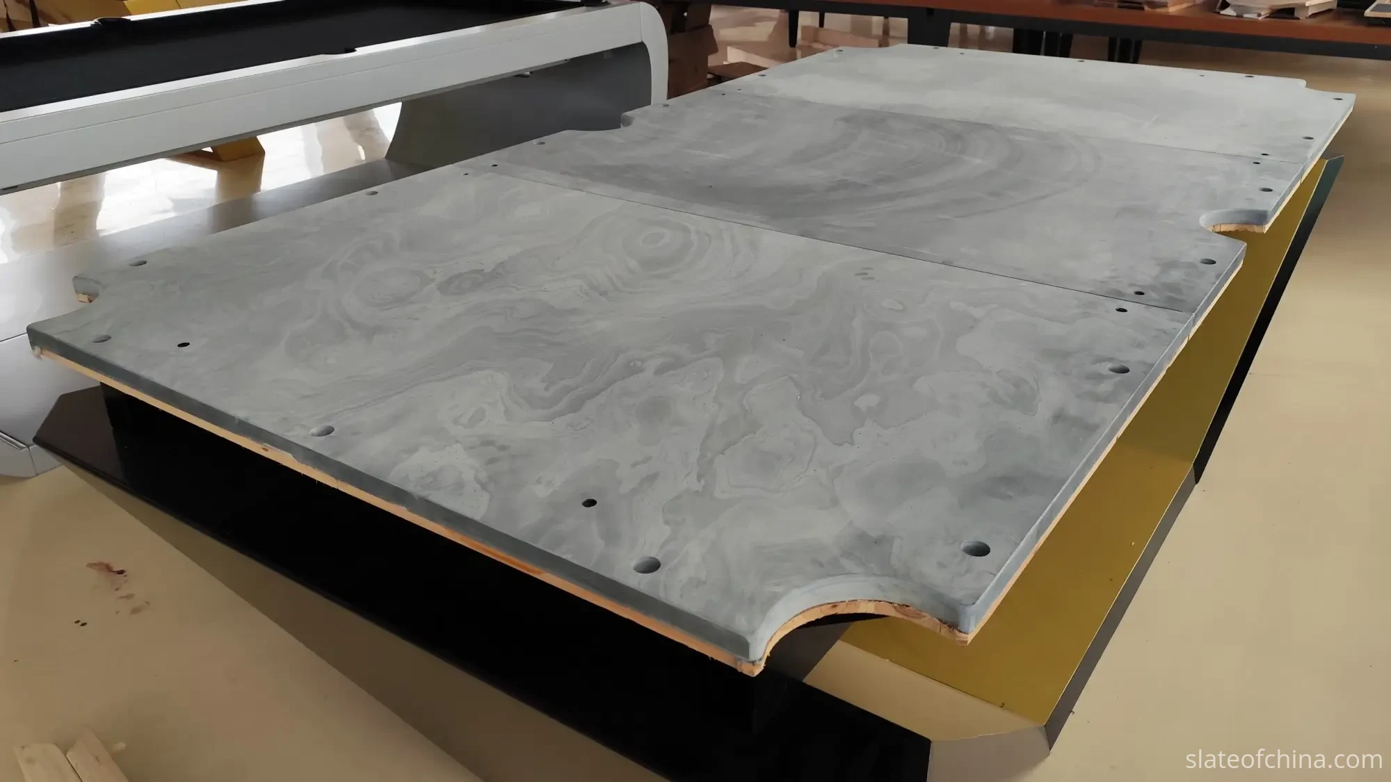 Three-piece billiard slate set assembled on a table frame showing pre-drilled mounting holes along the perimeter