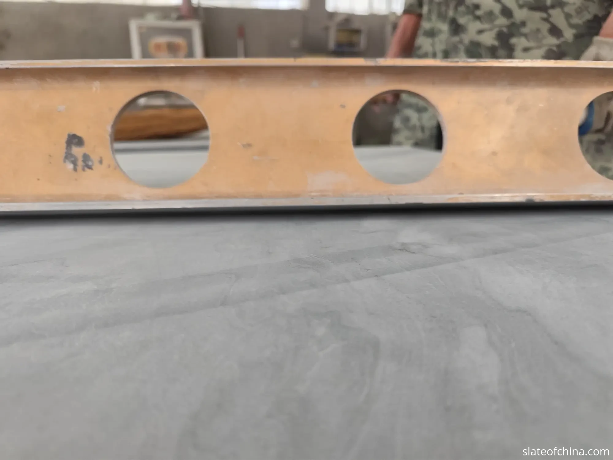 Certified flatness straightedge inspection Real factory photo of a levelling straightedge resting across the honed face of a slate billiard bed panel during a flatness check