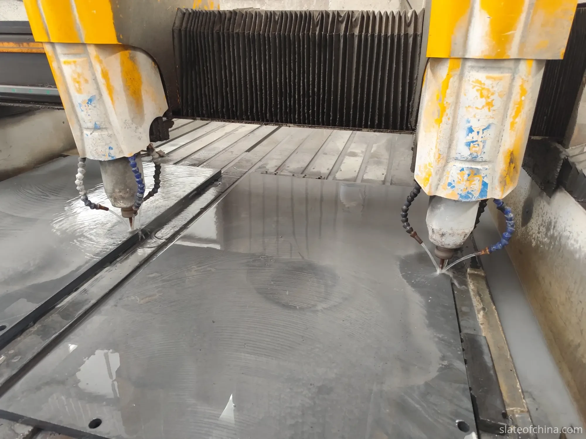 CNC drilling machine machining mounting holes into a large blue-grey billiard slate panel on factory worktable