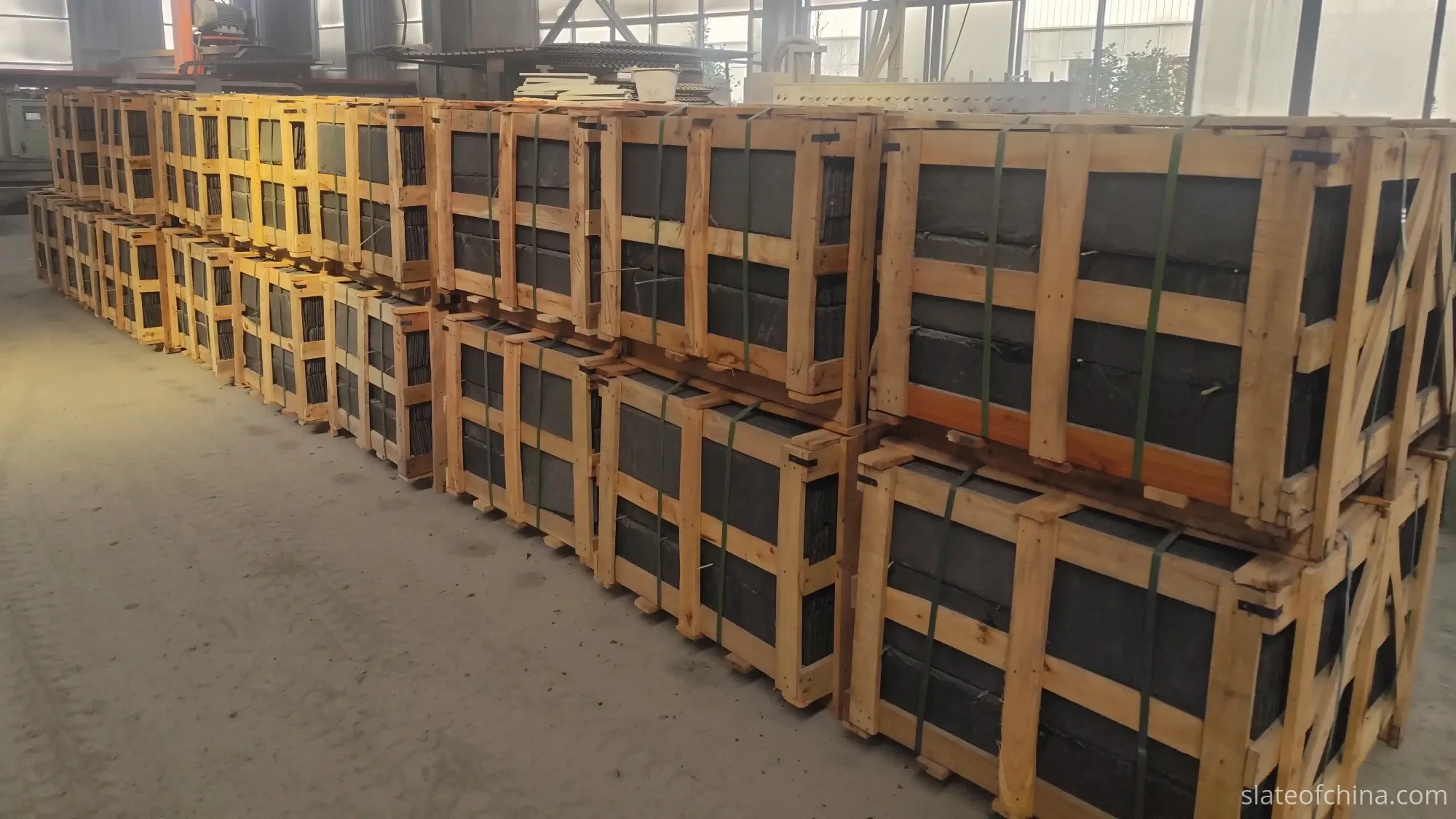 Finished roofing slate tiles stacked in layers inside an export wooden crate with strapping and corner protection in a workshop