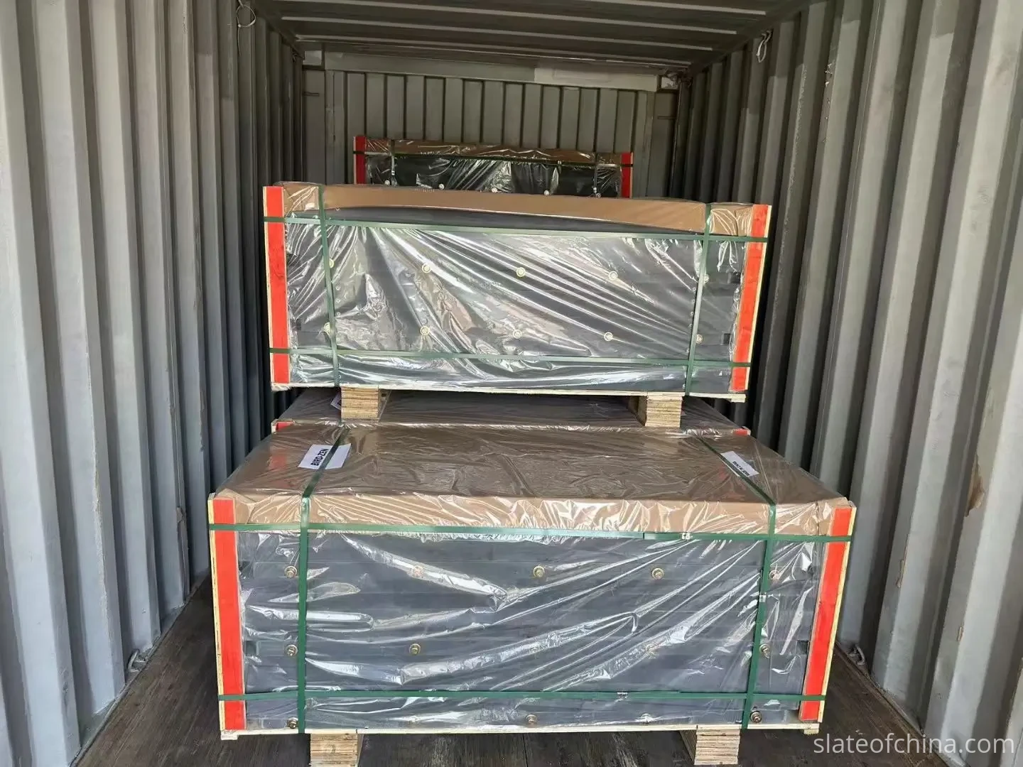 Loading Wooden Crates of Roofing Slate into a Container An open shipping container at a factory loading dock with wooden crates of slate stacked inside