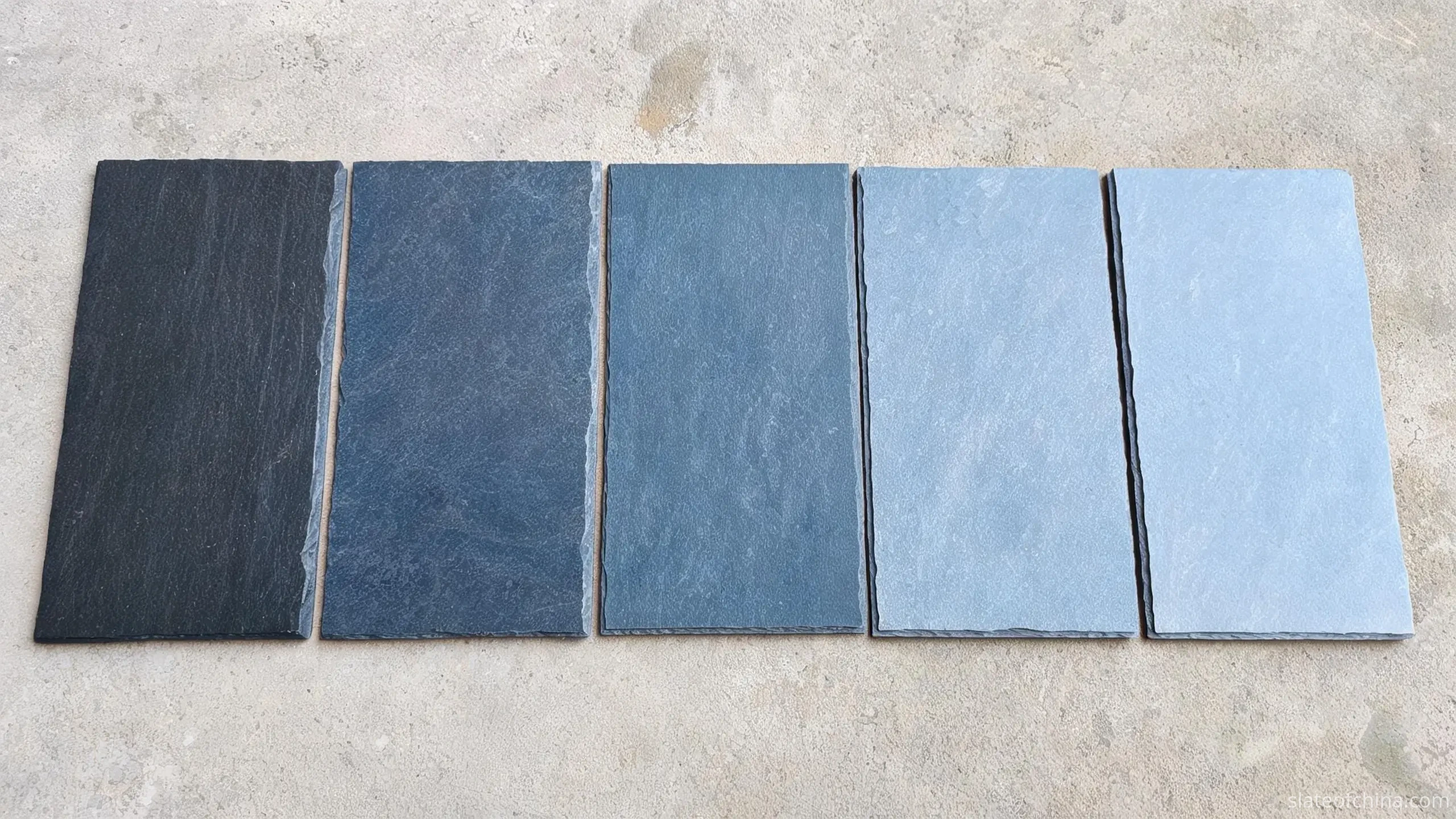 Jiujiang Roofing Slate Samples — Colour and Grade Range Five rectangular roofing slate samples in graduated blue-grey tones laid in a row on light concrete
