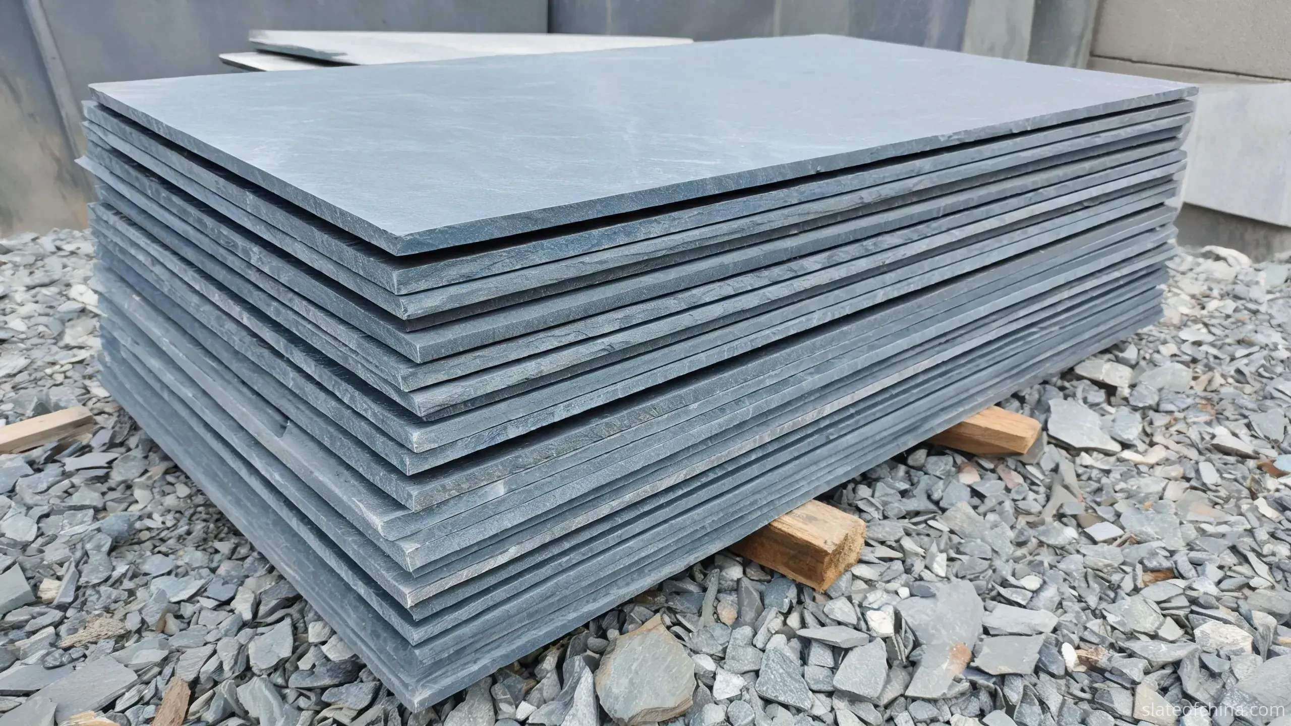 Jiujiang Slate Paving & Flooring 2 Calibrated slate paving slabs on timber bearers in a stone yard, three-quarter view showing uniform sawn thickness edges and matte blue-grey faces