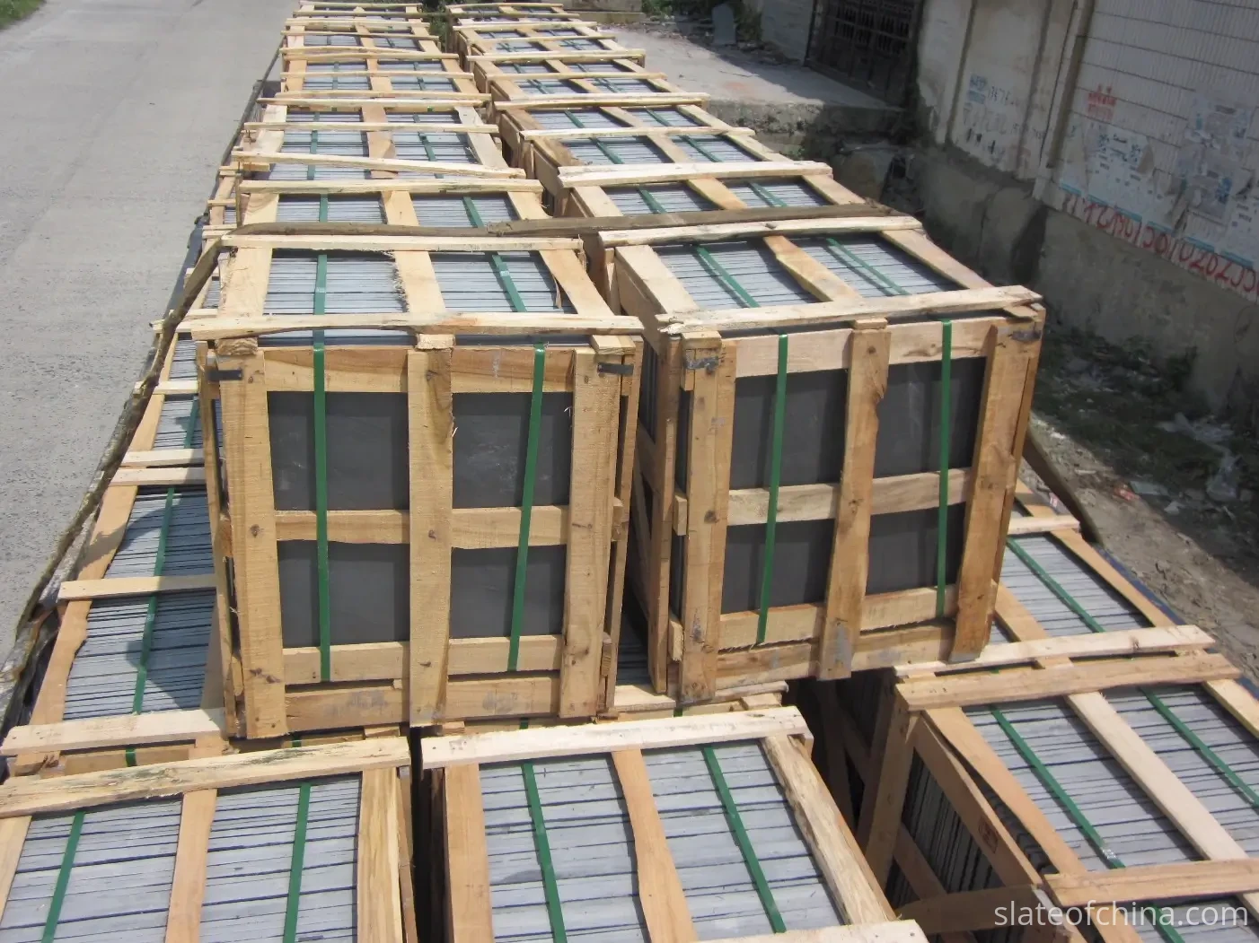 Jiujiang Slate Supply Chain 2 Finished slate tiles in low neat stacks beside a separate pile of broken offcuts inside a Jiujiang workshop