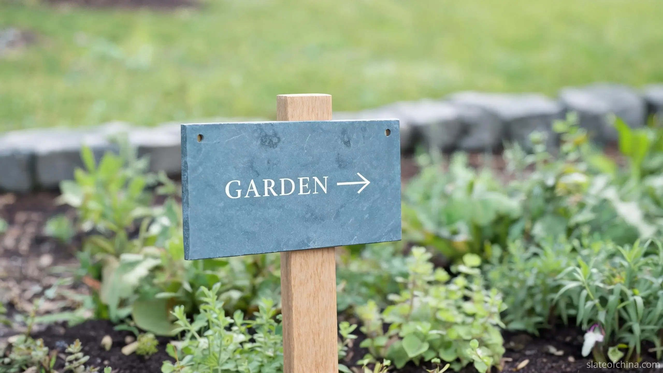 Slate Signs & House Number Plates 4 A rectangular slate garden sign with an engraved word and arrow mounted on a wooden post among planted borders