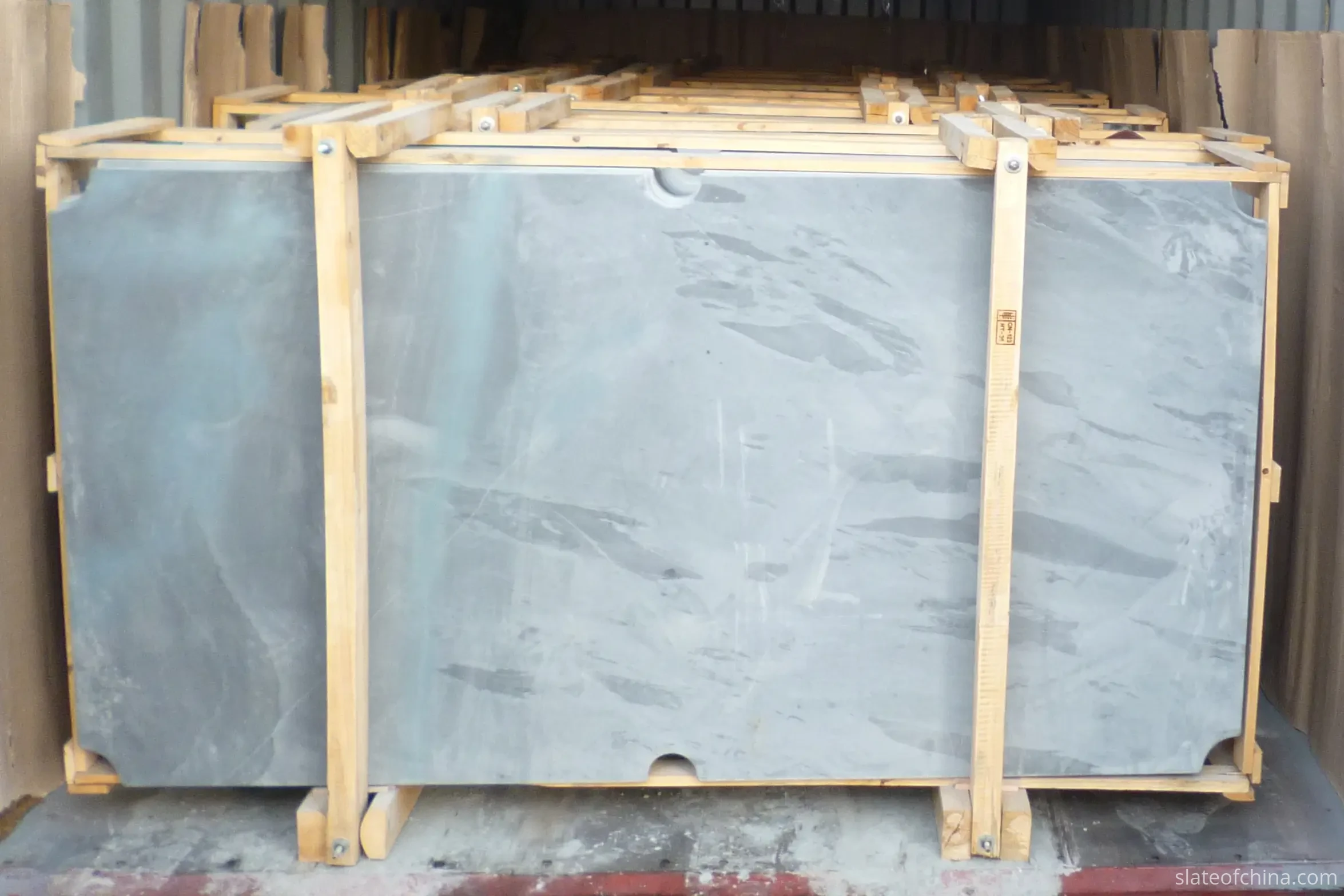 Slate Panel Cradle Packing Inside A Shipping Container Large slate panels packed upright in purpose-built wooden cradles inside a shipping container, with protective cardboard lining along the container walls