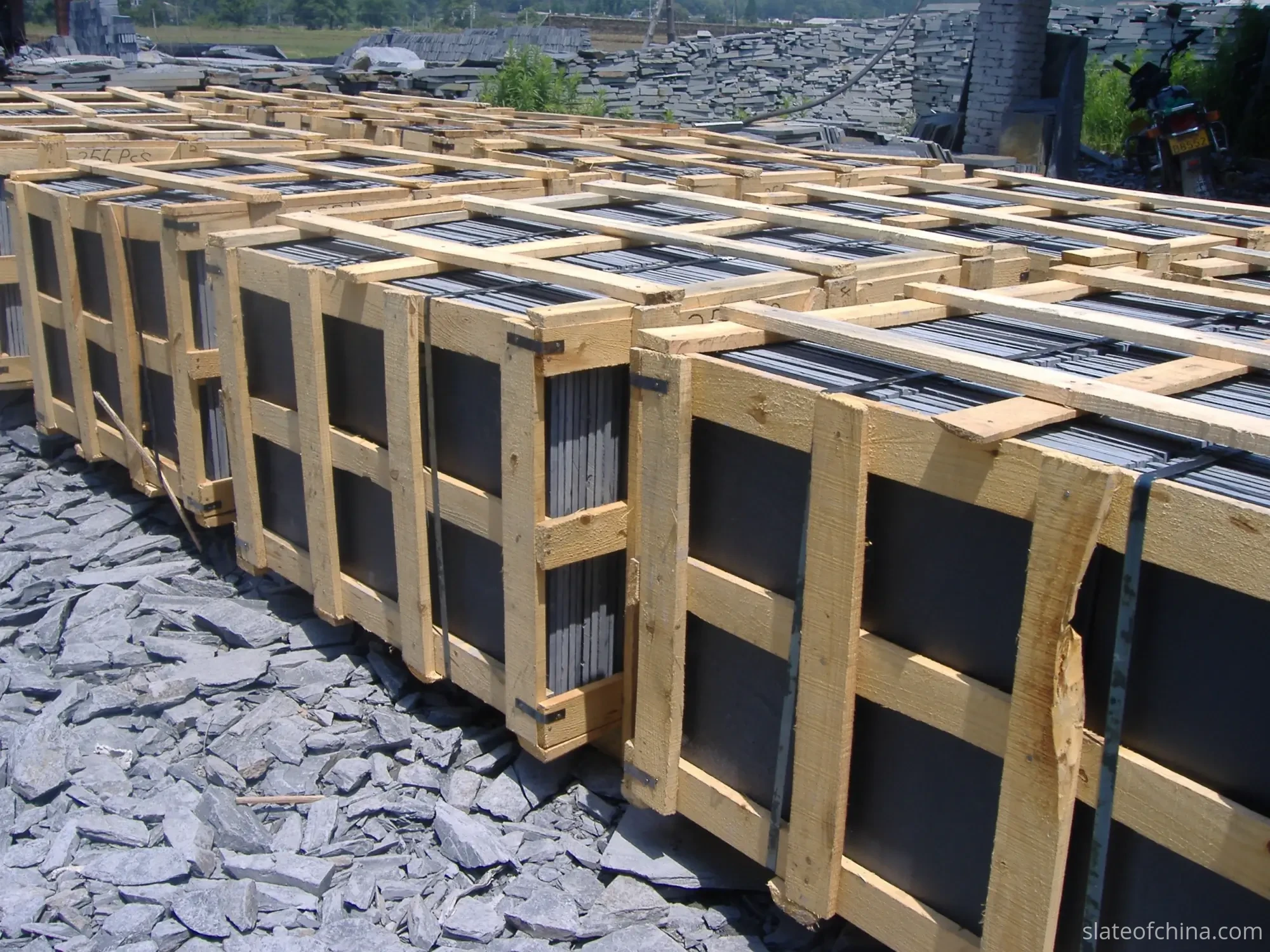 Paving Slate Sizes & Thicknesses 4 Rows of open wooden export crates filled with slate slabs standing vertically edge-on in a stone yard, black strapping around each crate, one crate top rail stencilled 256 PCS