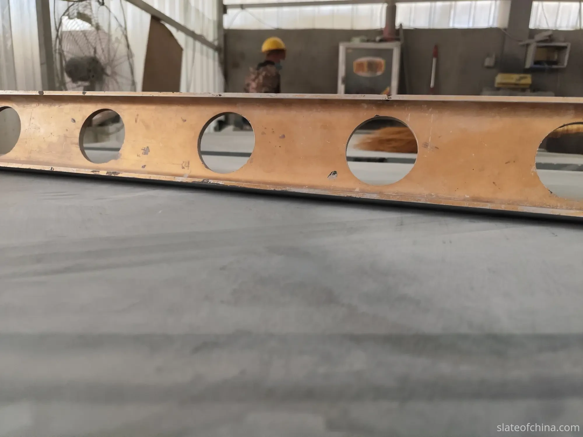 Surface Quality Inspection 2 A precision straightedge resting across a finished billiard slate panel at the factory inspection bench